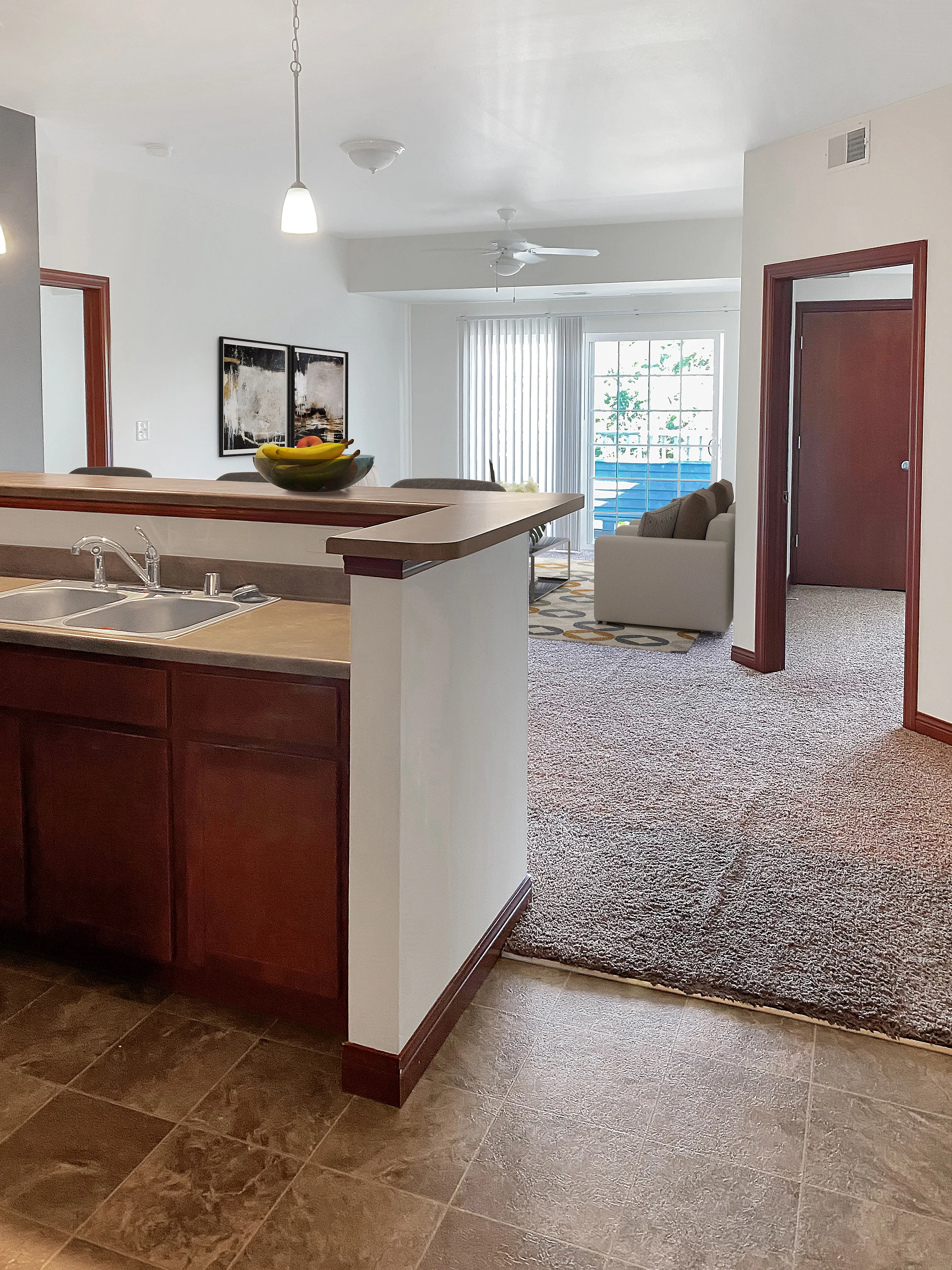 Bright open-concept living space featuring a modern kitchen and cozy living room with large windows and stylish decor.