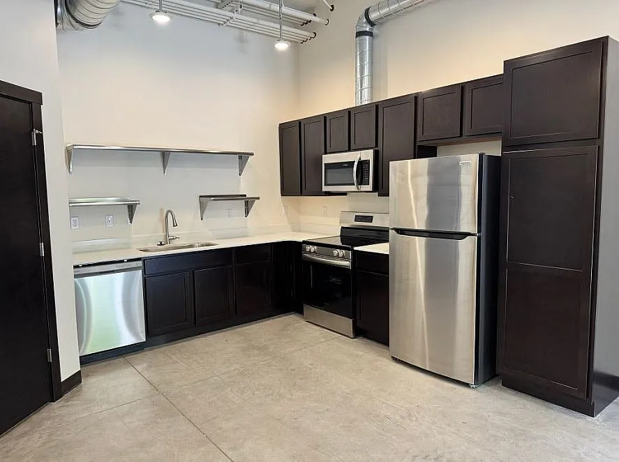 Contemporary kitchen featuring sleek dark cabinets, stainless steel appliances, and modern open shelving.