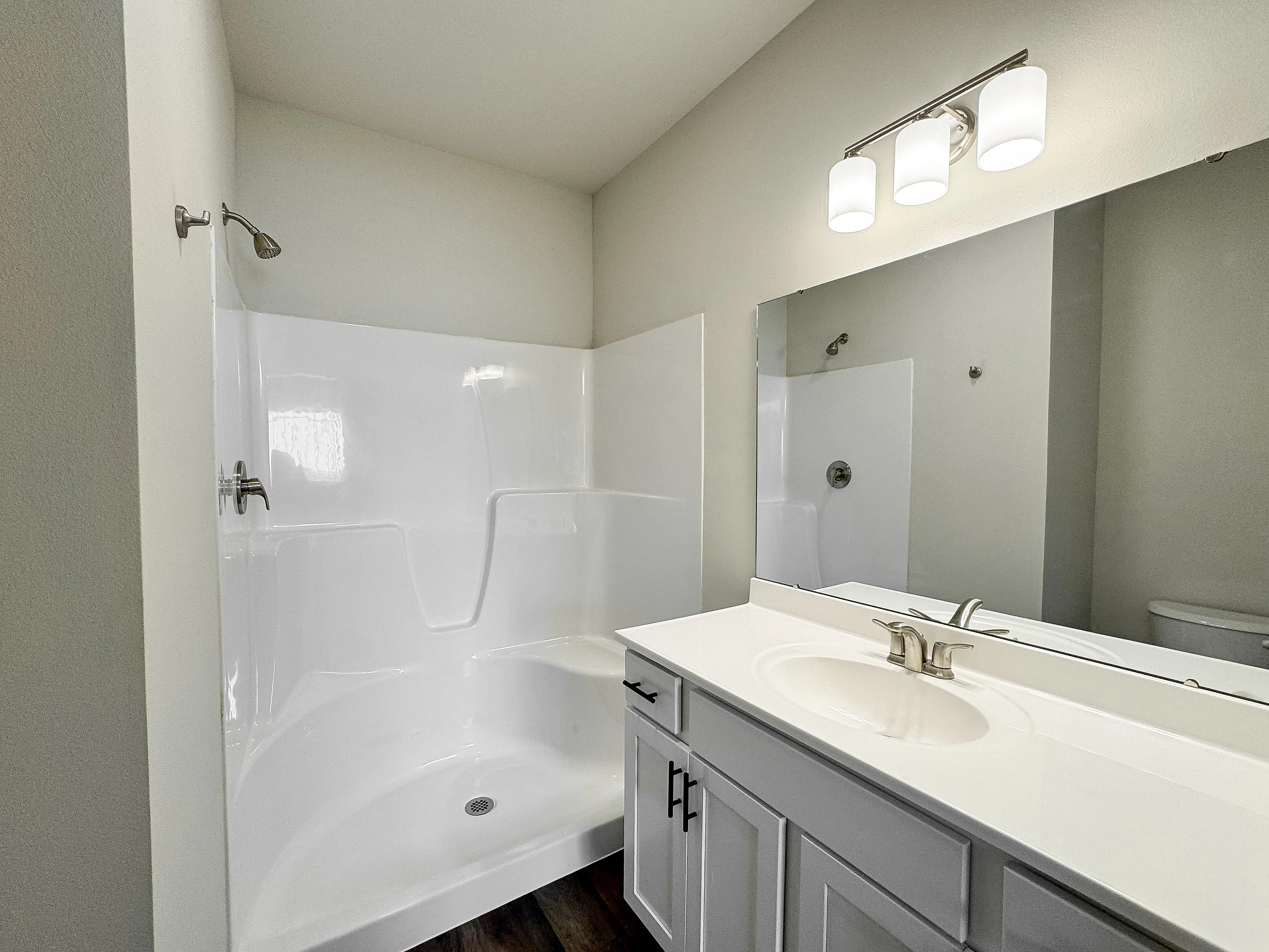 Elegant bathroom featuring a modern shower, sleek white vanity, and bright lighting for a refreshing ambiance.
