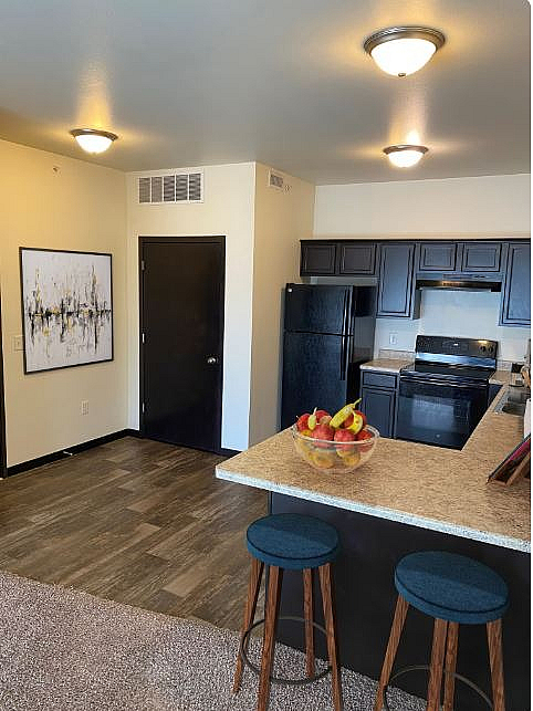 Modern kitchen with sleek black appliances, stylish bar seating, and inviting decor.