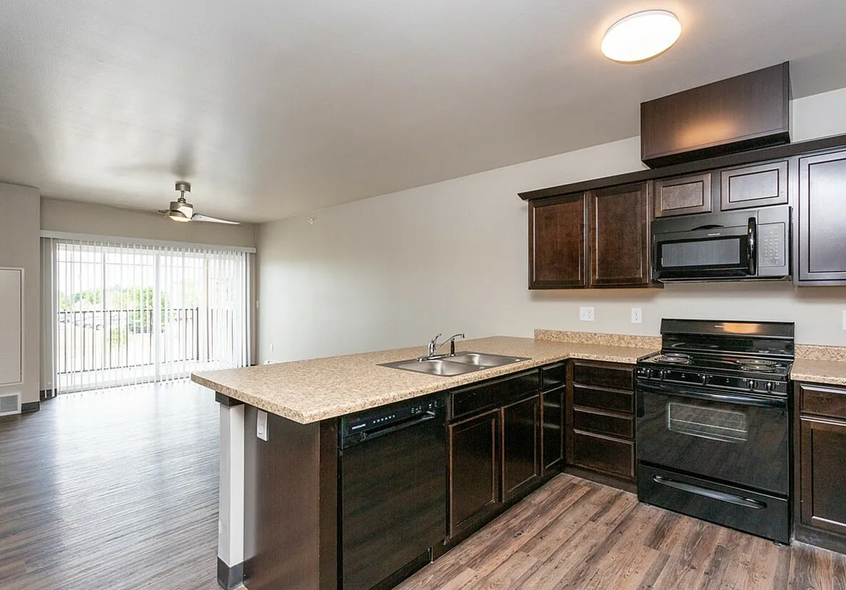 Inviting open floor plan with modern kitchen featuring dark cabinetry, sleek appliances, and large patio doors for natural light.