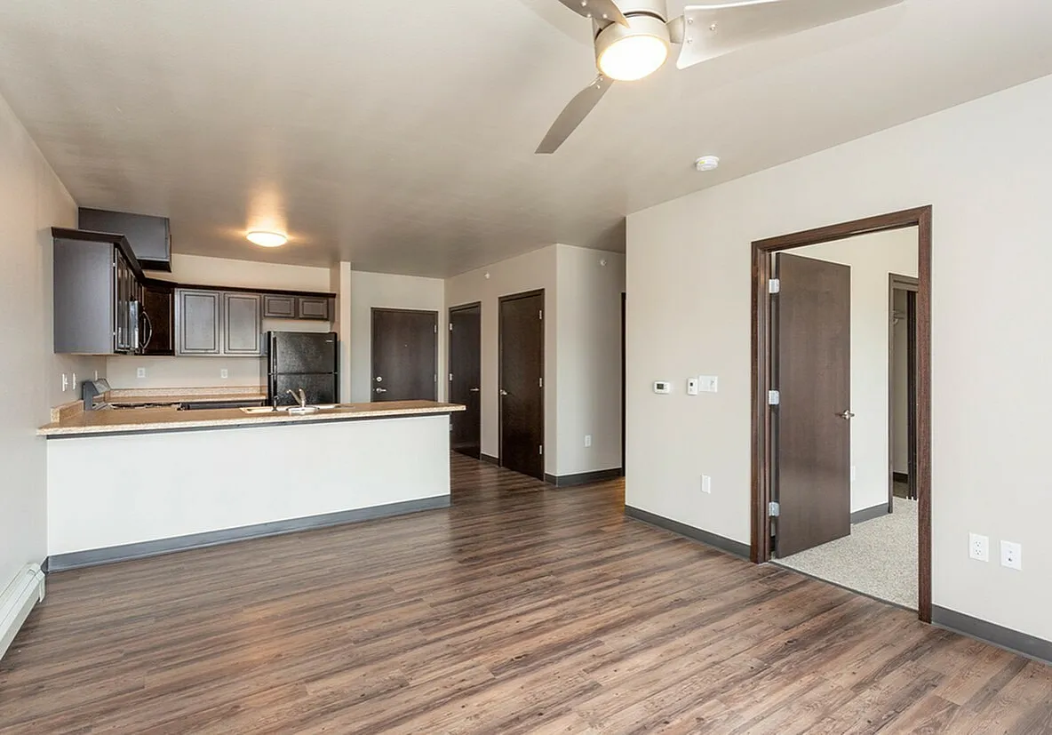Modern open-plan living area featuring elegant hardwood floors, a sleek kitchen with dark cabinetry, and ample natural light.