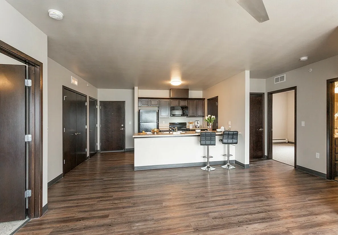 Contemporary open-concept apartment with sleek kitchen, modern cabinetry, inviting breakfast bar, and elegant wood flooring.