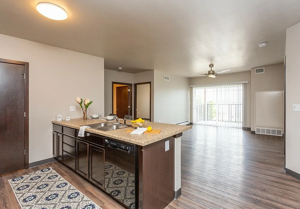 Modern open-concept apartment kitchen and living area with sleek countertops, stylish lighting, and expansive floor-to-ceiling windows.