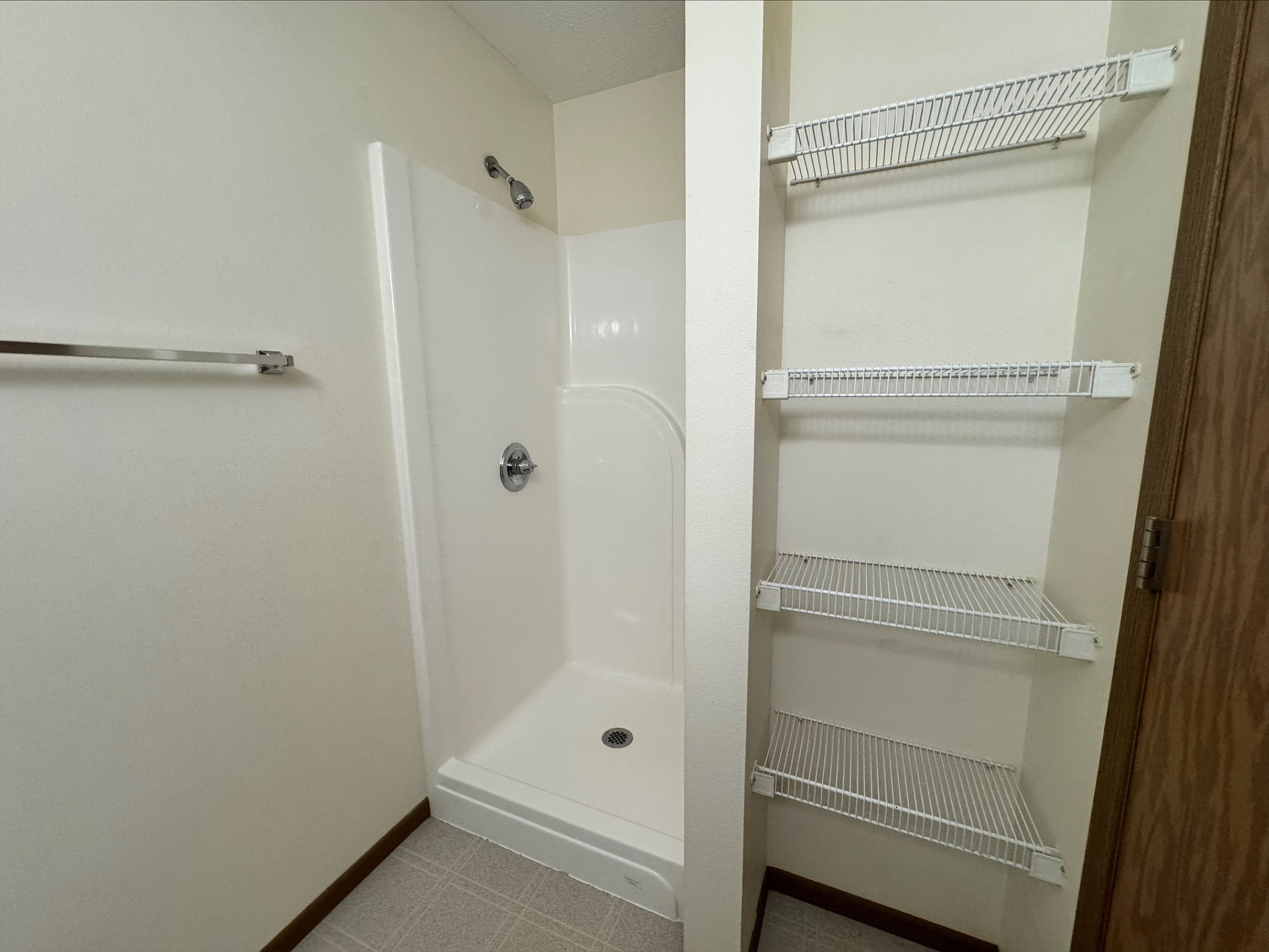 Modern bathroom with sleek shower and convenient built-in wire shelving for ample storage.
