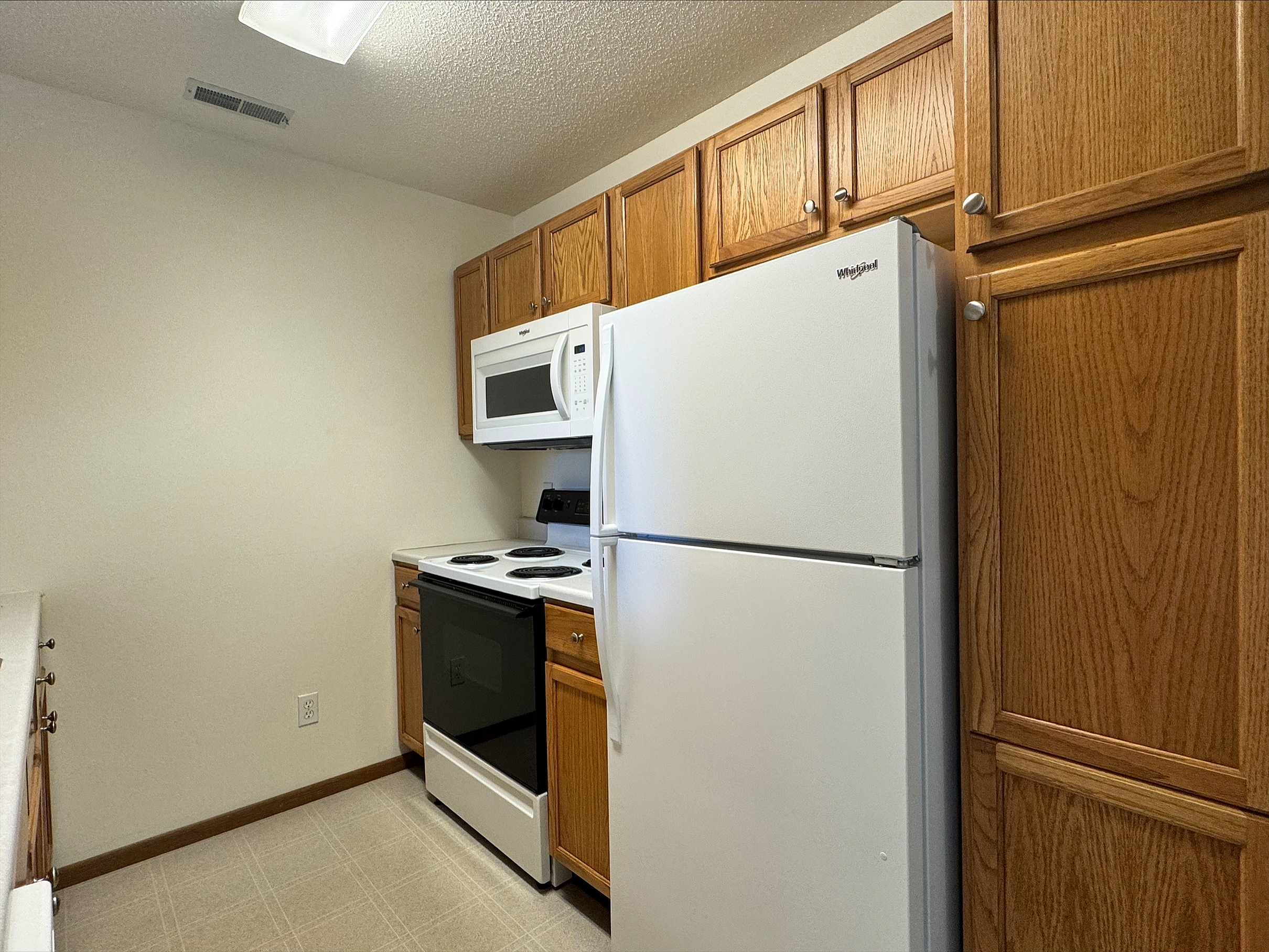 Cozy kitchen with modern appliances, featuring warm wooden cabinetry and ample storage space.