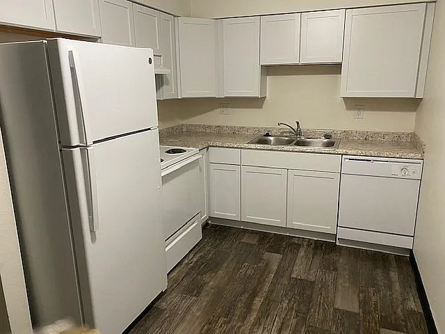 Modern kitchen with sleek white cabinetry, granite countertops, and stainless steel appliances.