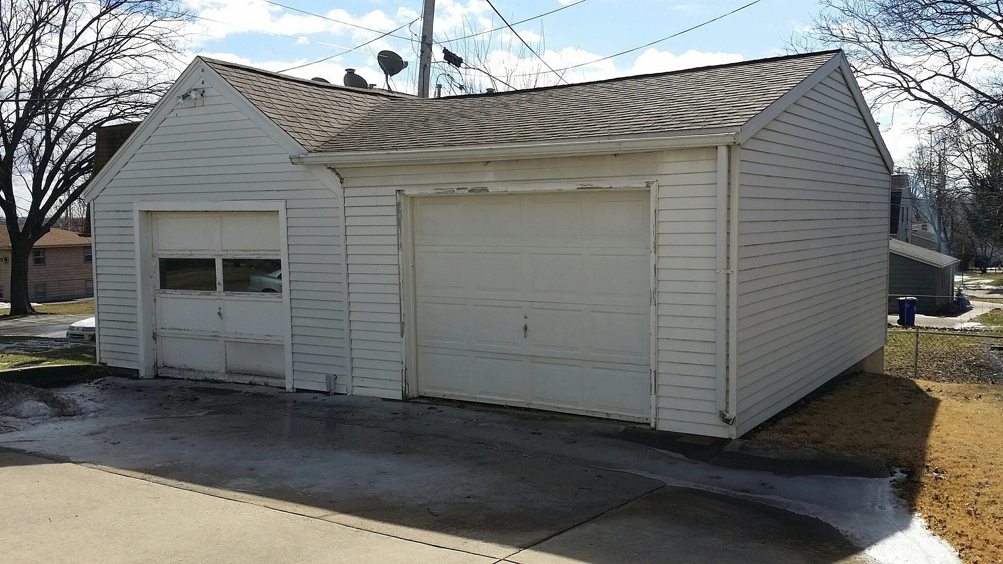 Charming garage with classic white siding, featuring dual doors for ample storage and parking space. Ideal for homeowners seeking functionality and convenience in a suburban setting.