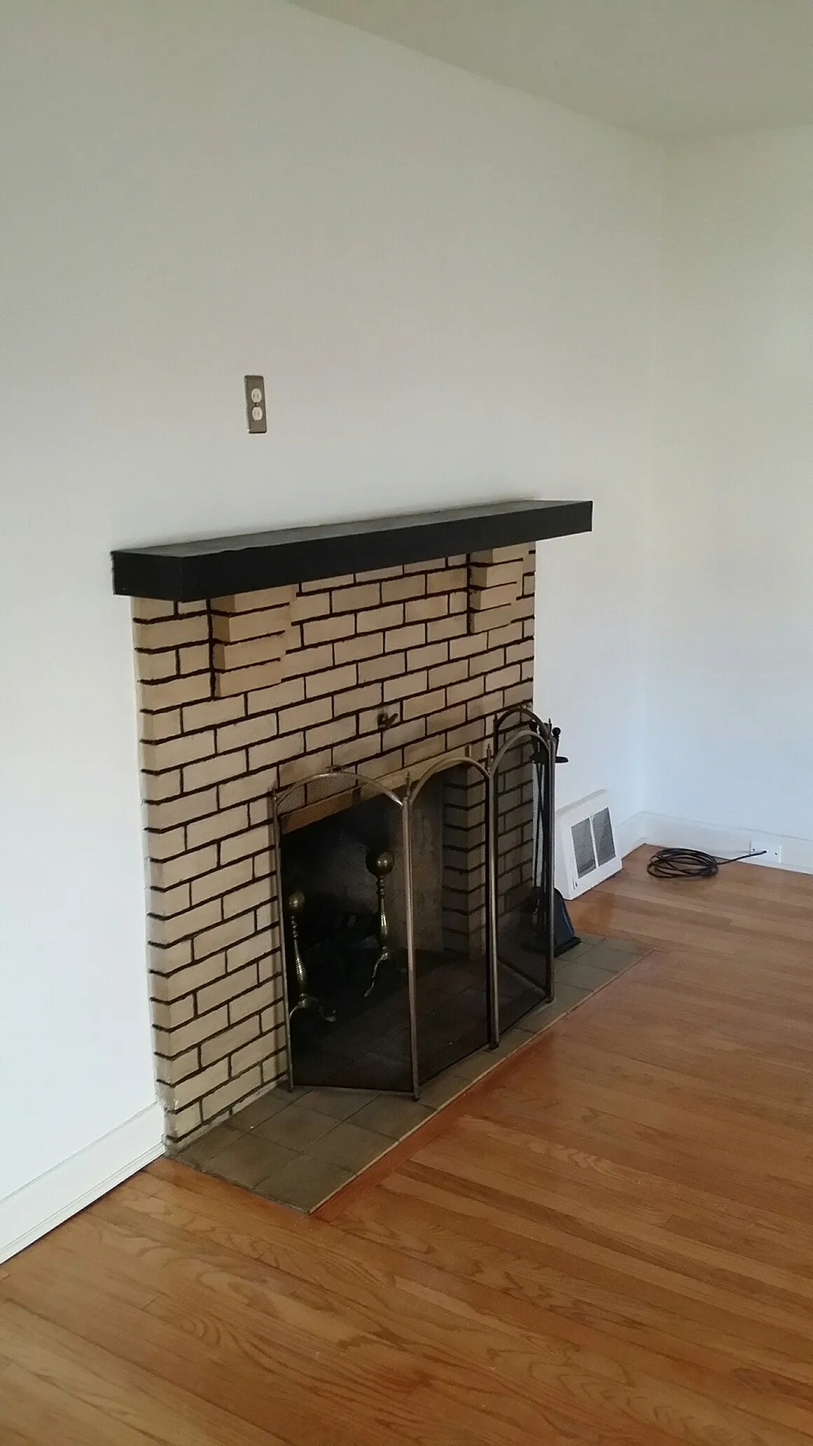 Charming living area featuring elegant hardwood floors and a classic brick fireplace.