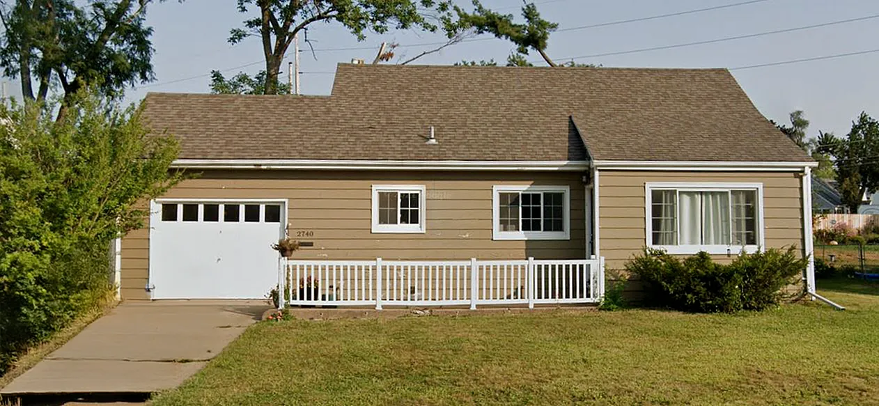 Charming single-story home with a welcoming front porch, spacious driveway, and lush green lawn.