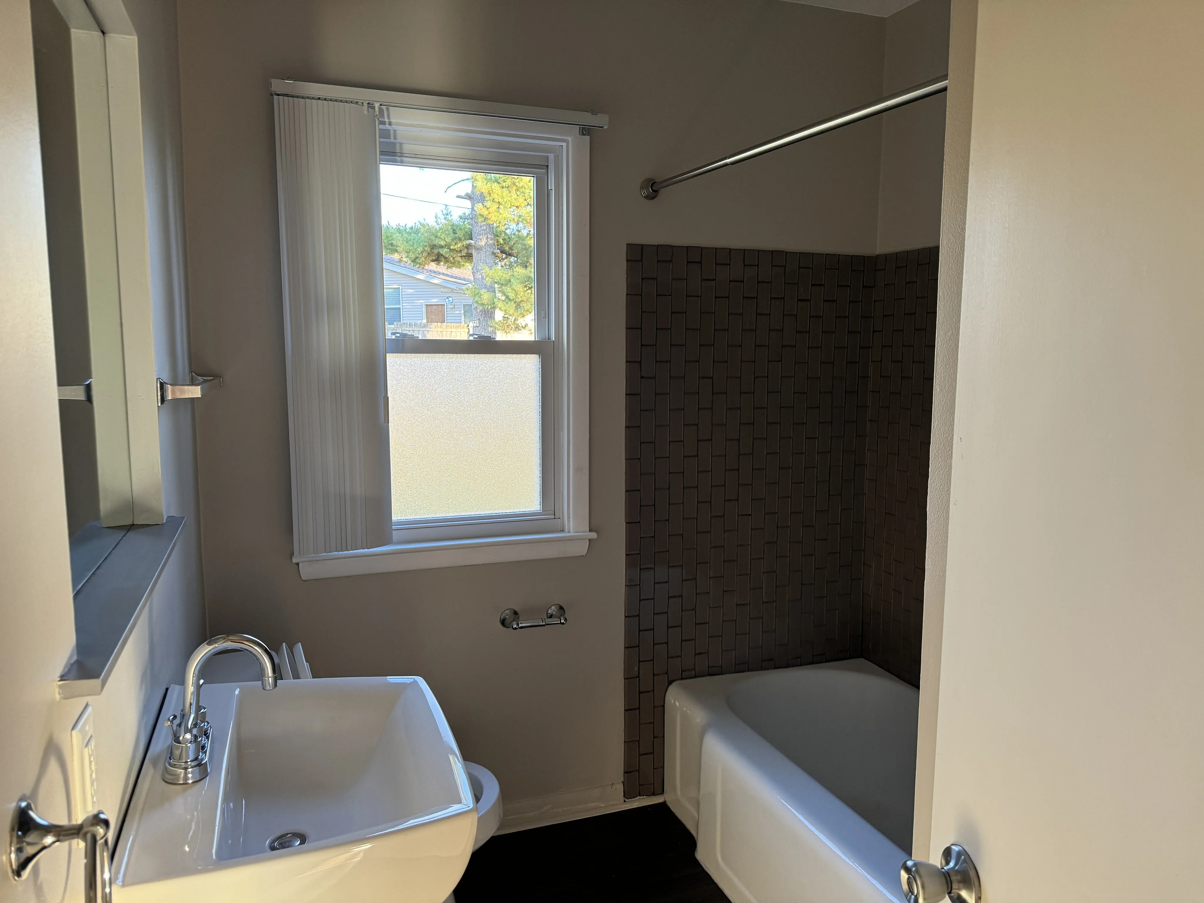 Bright bathroom featuring a modern sink, spacious bathtub, and a large window allowing natural light to fill the space.