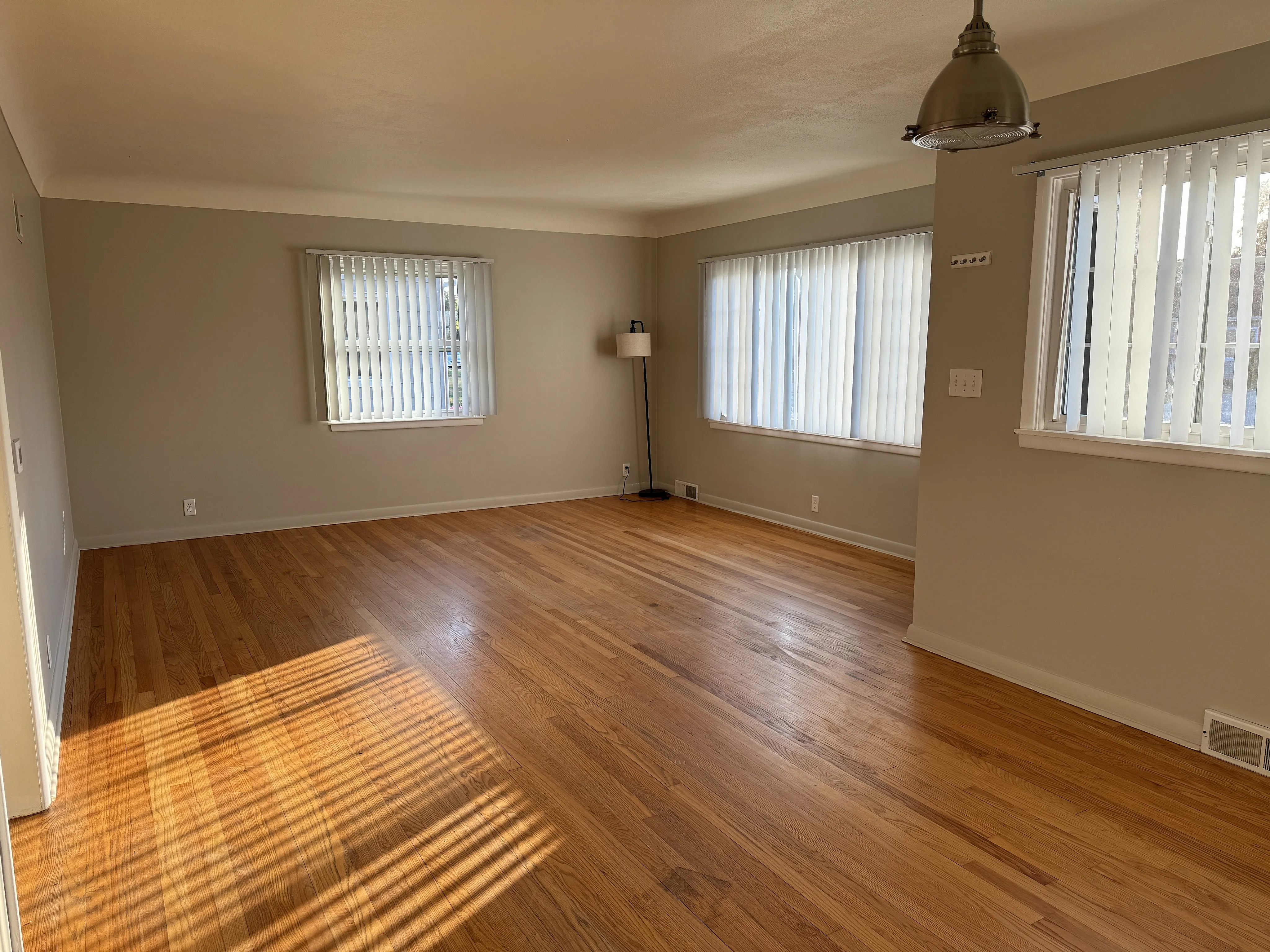 Bright apartment with warm hardwood floors and large windows, offering ample natural light and a spacious living area.