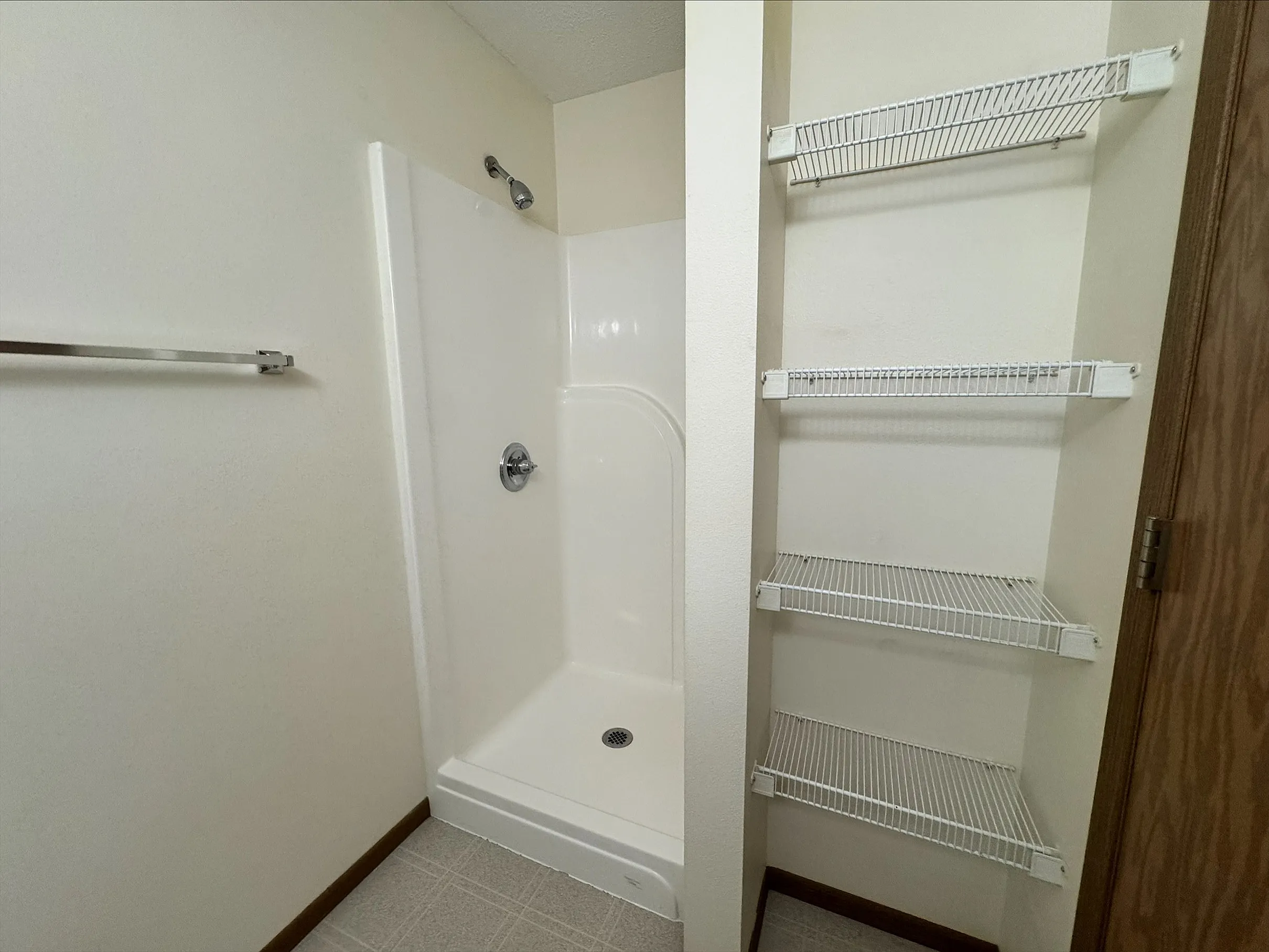 Modern bathroom with a sleek shower and spacious wire shelving, offering convenient storage and a minimalist design.