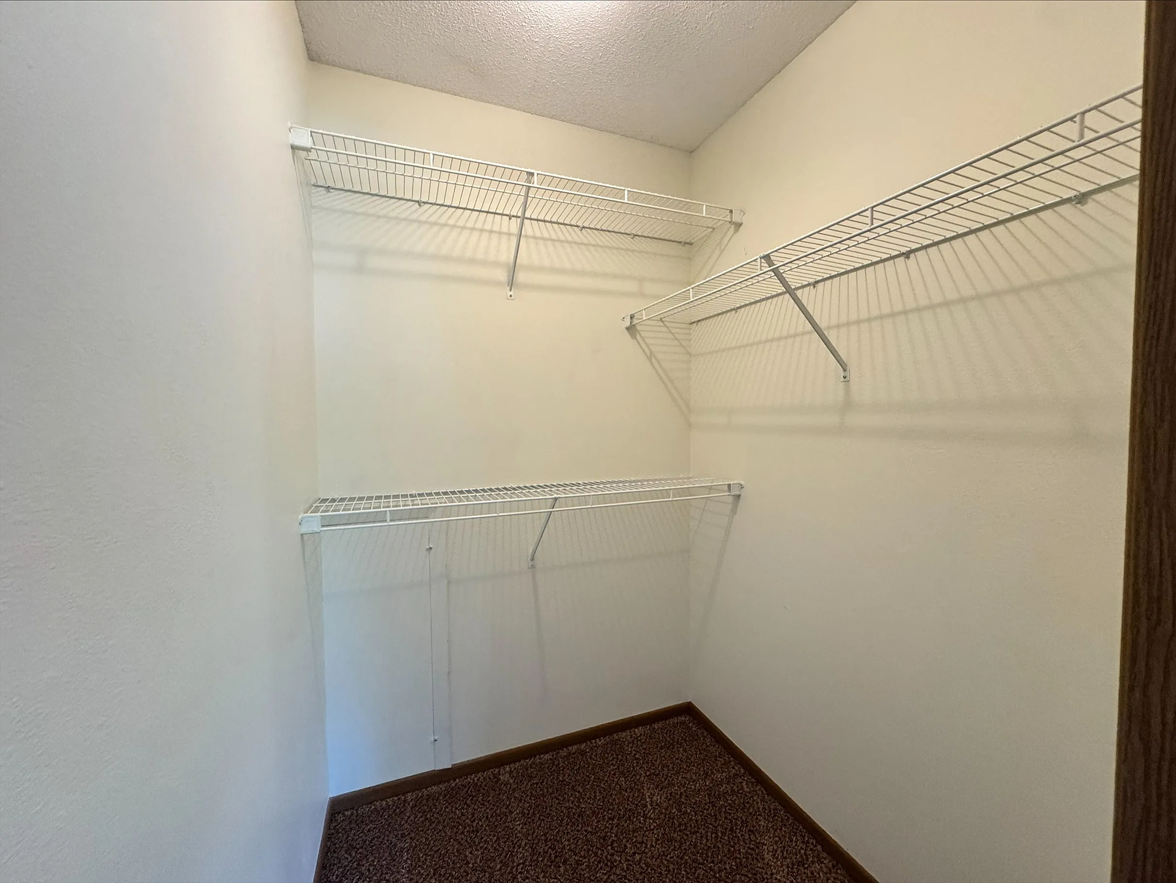 Spacious walk-in closet with sleek white wire shelving, offering ample storage space in a modern apartment.