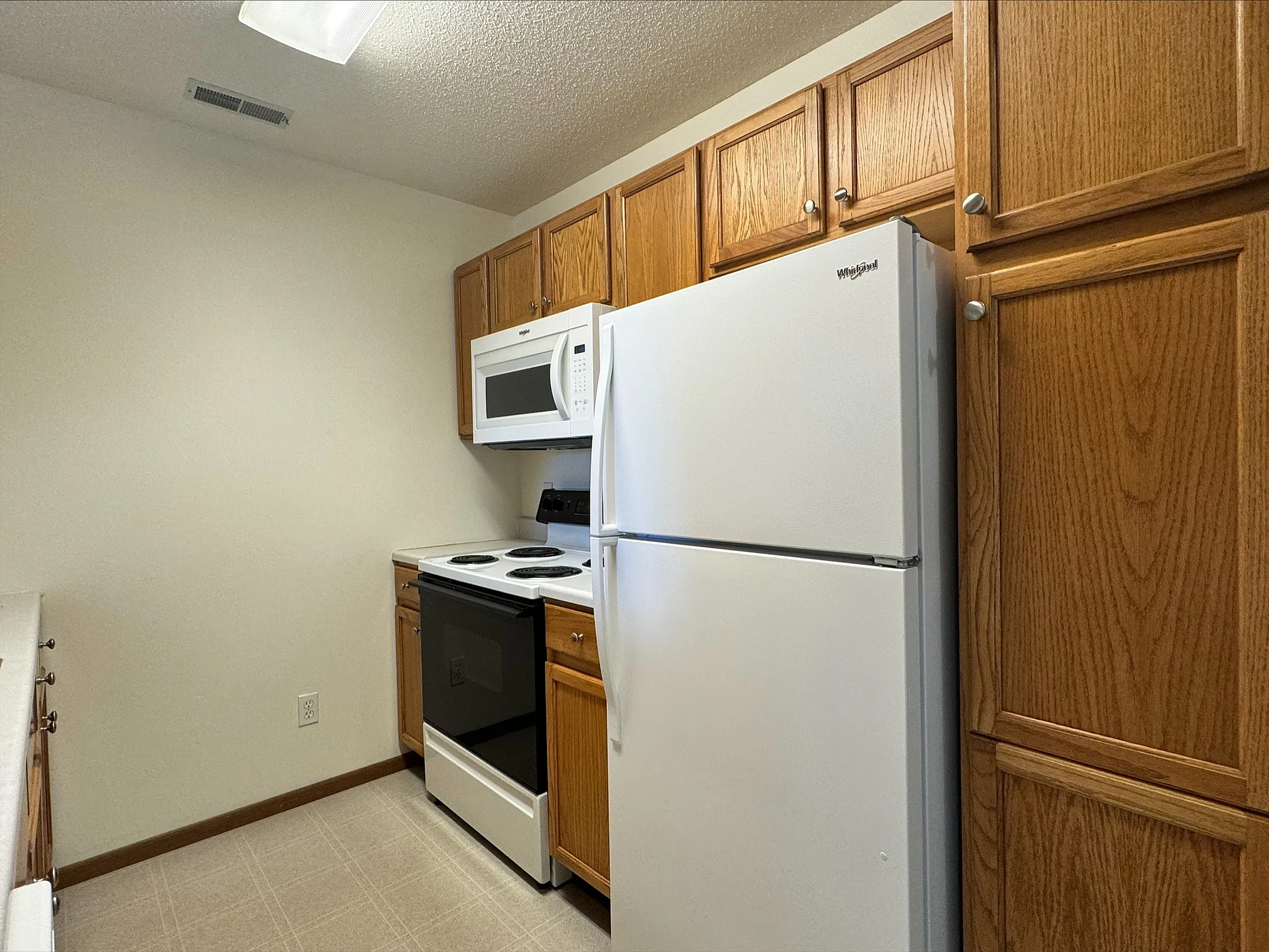 Charming kitchen with warm wooden cabinetry, modern white appliances, and ample storage space.
