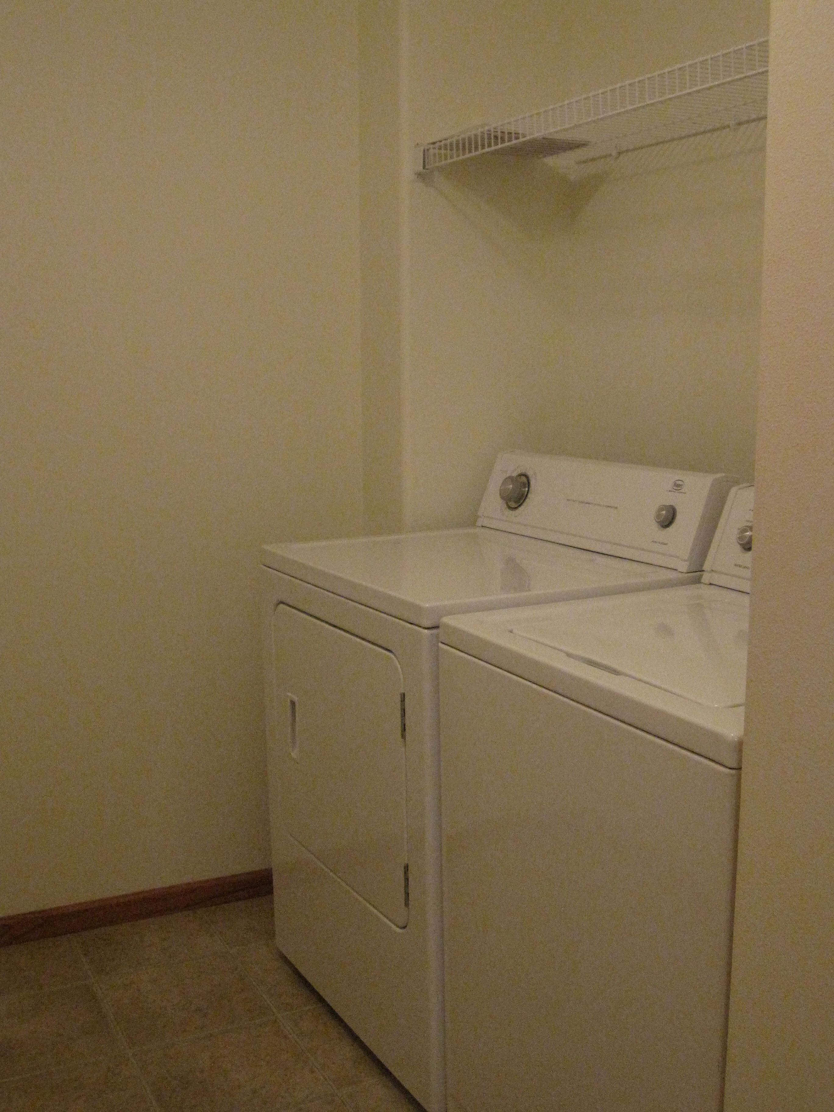 Spacious laundry room featuring a modern washer and dryer set with convenient shelving for storage.