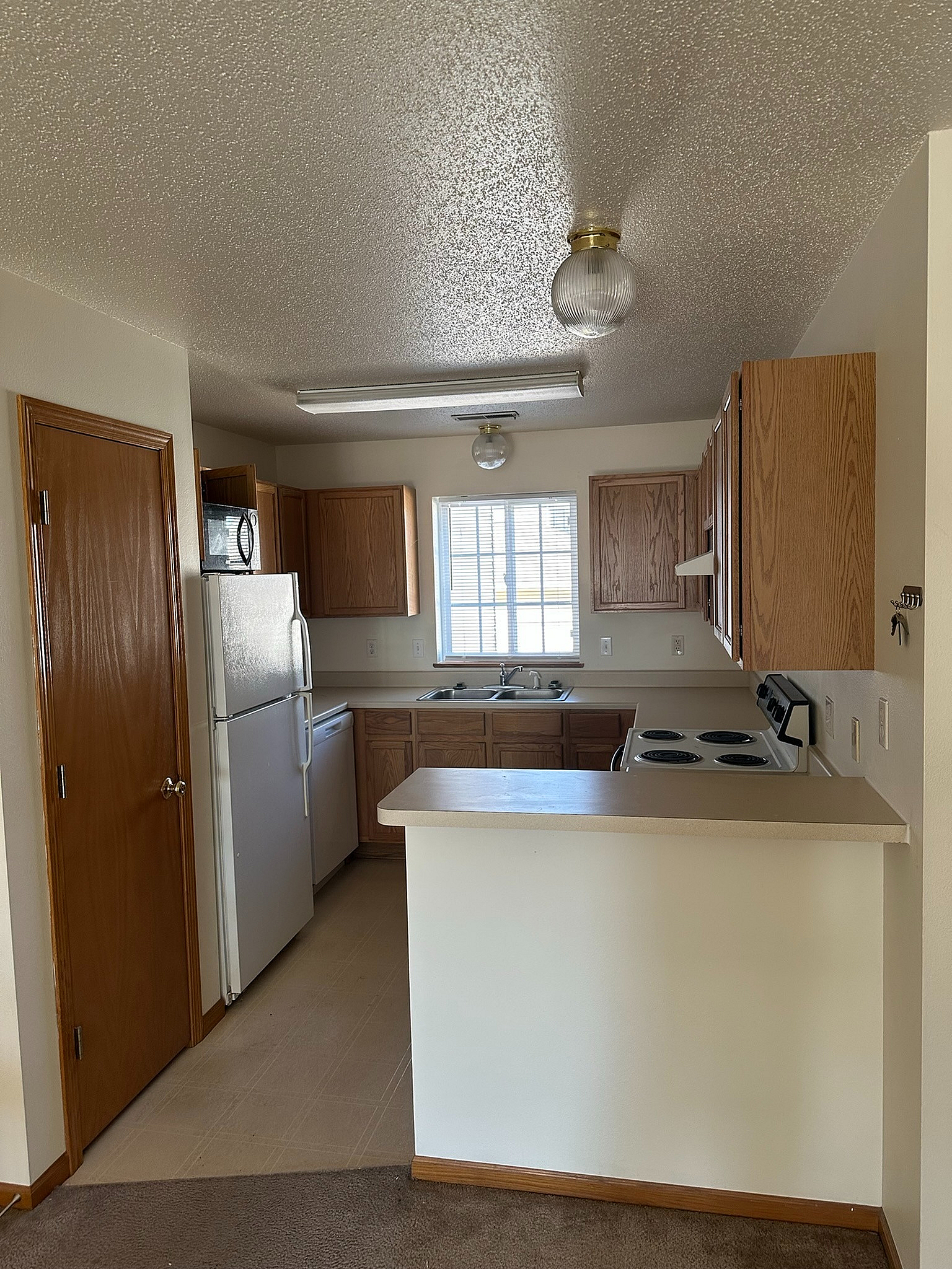 Cozy kitchen with warm wooden cabinetry, modern appliances, and natural light enhancing the inviting ambiance.