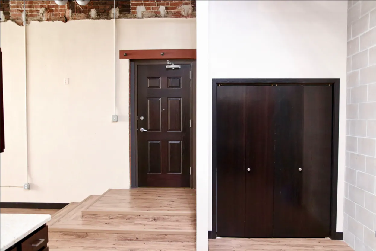 Inviting apartment entryway with warm wood accents, contemporary double doors, and a sleek closet for optimal storage.