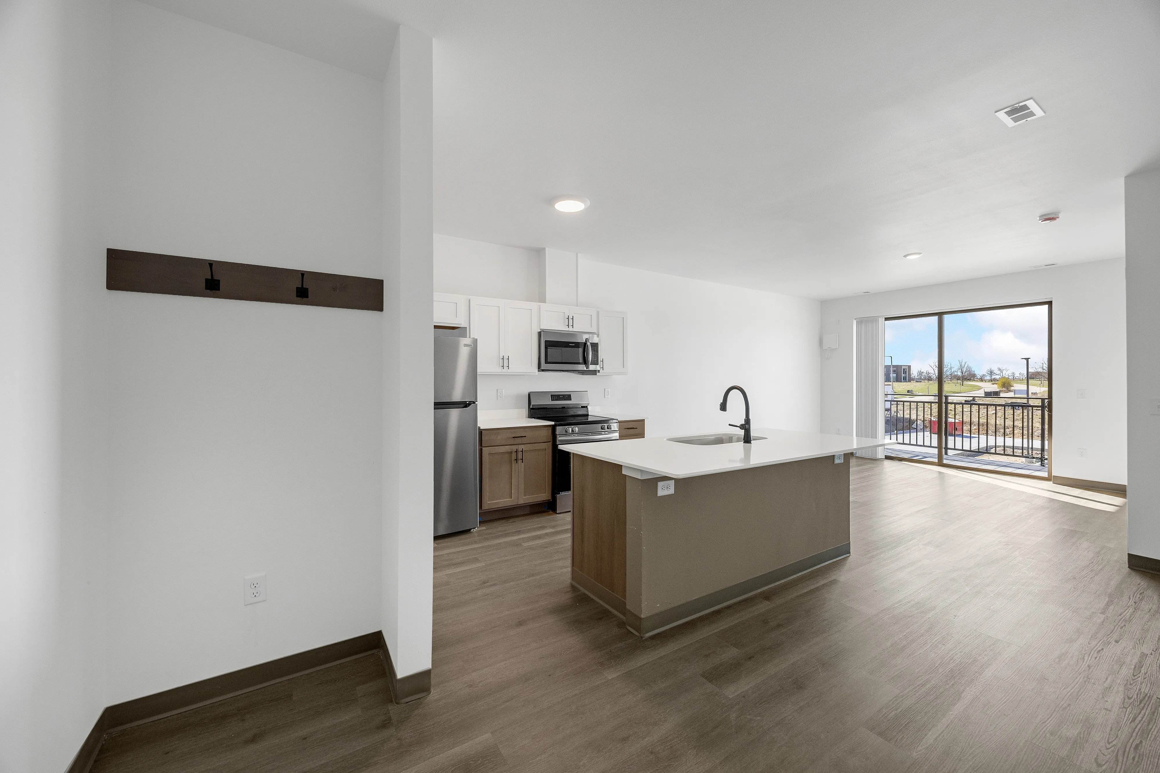 Modern open-plan kitchen and living area with sleek appliances and a bright, spacious feel. Large windows offer ample natural light and a view of the outdoor landscape.