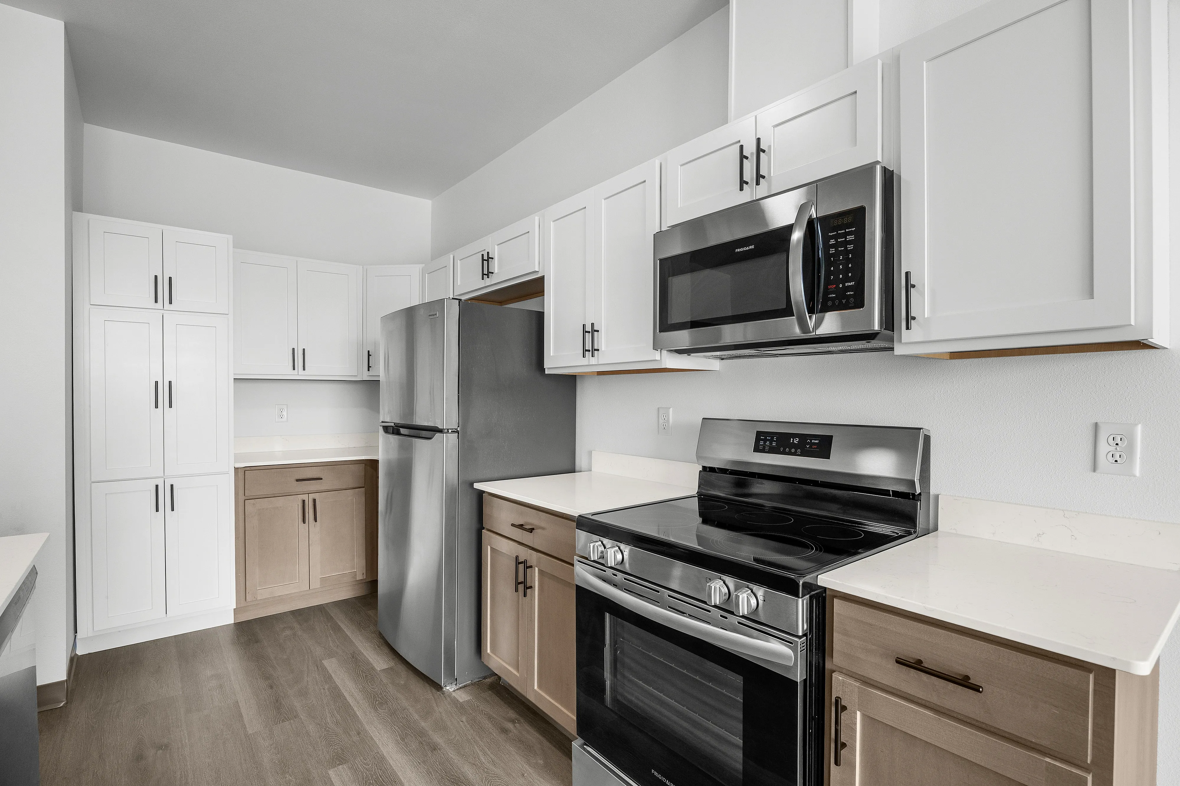 Modern kitchen with sleek stainless steel appliances, stylish white cabinetry, and elegant wood flooring.