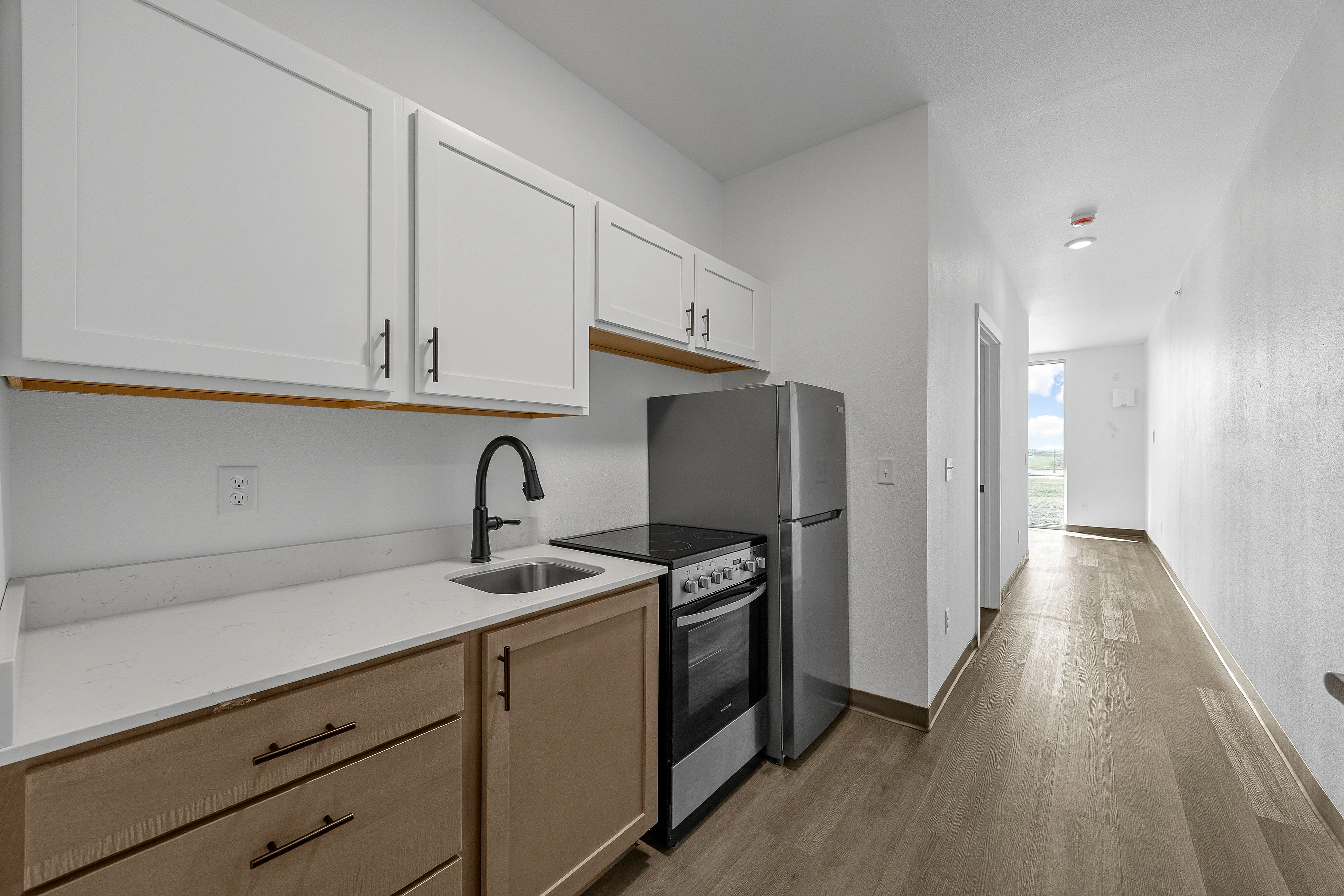 Sleek modern kitchen with elegant cabinetry, stainless steel appliances, and inviting natural light down a spacious hallway.