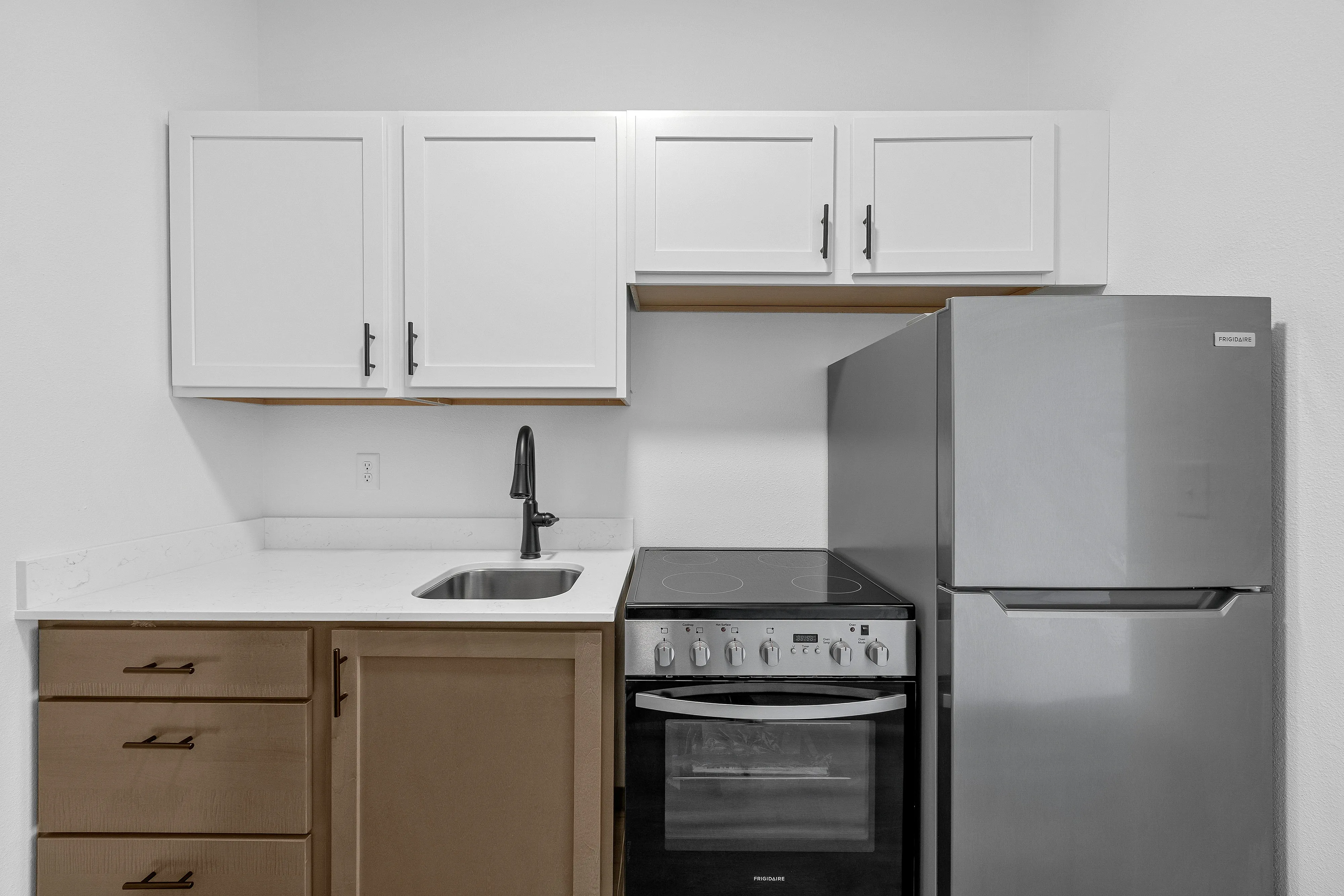 Modern kitchen with sleek stainless steel appliances, white cabinetry, and elegant black faucet, offering a contemporary and functional space.
