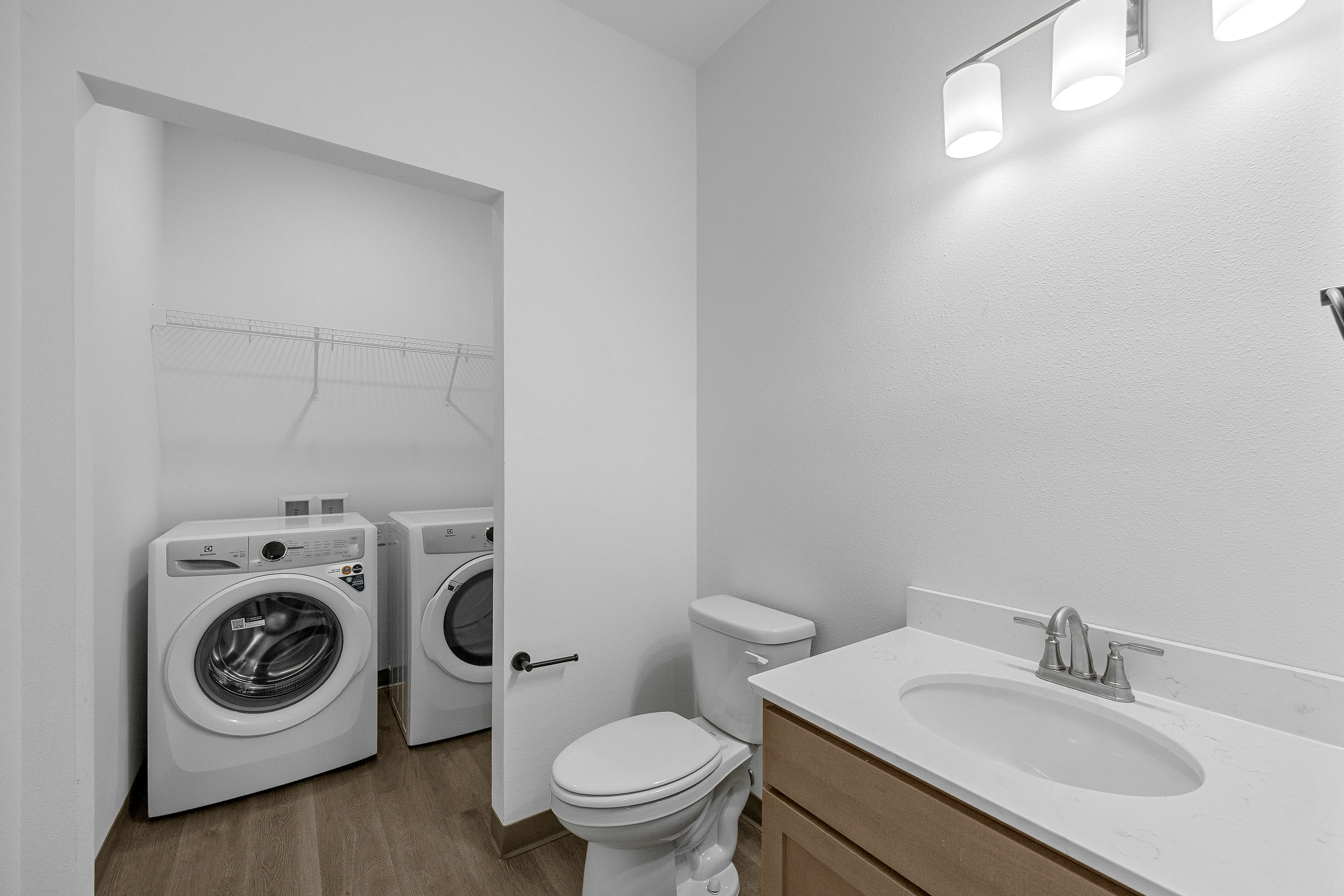 Chic bathroom with in-unit laundry, featuring modern washer and dryer, sleek vanity, and bright lighting.