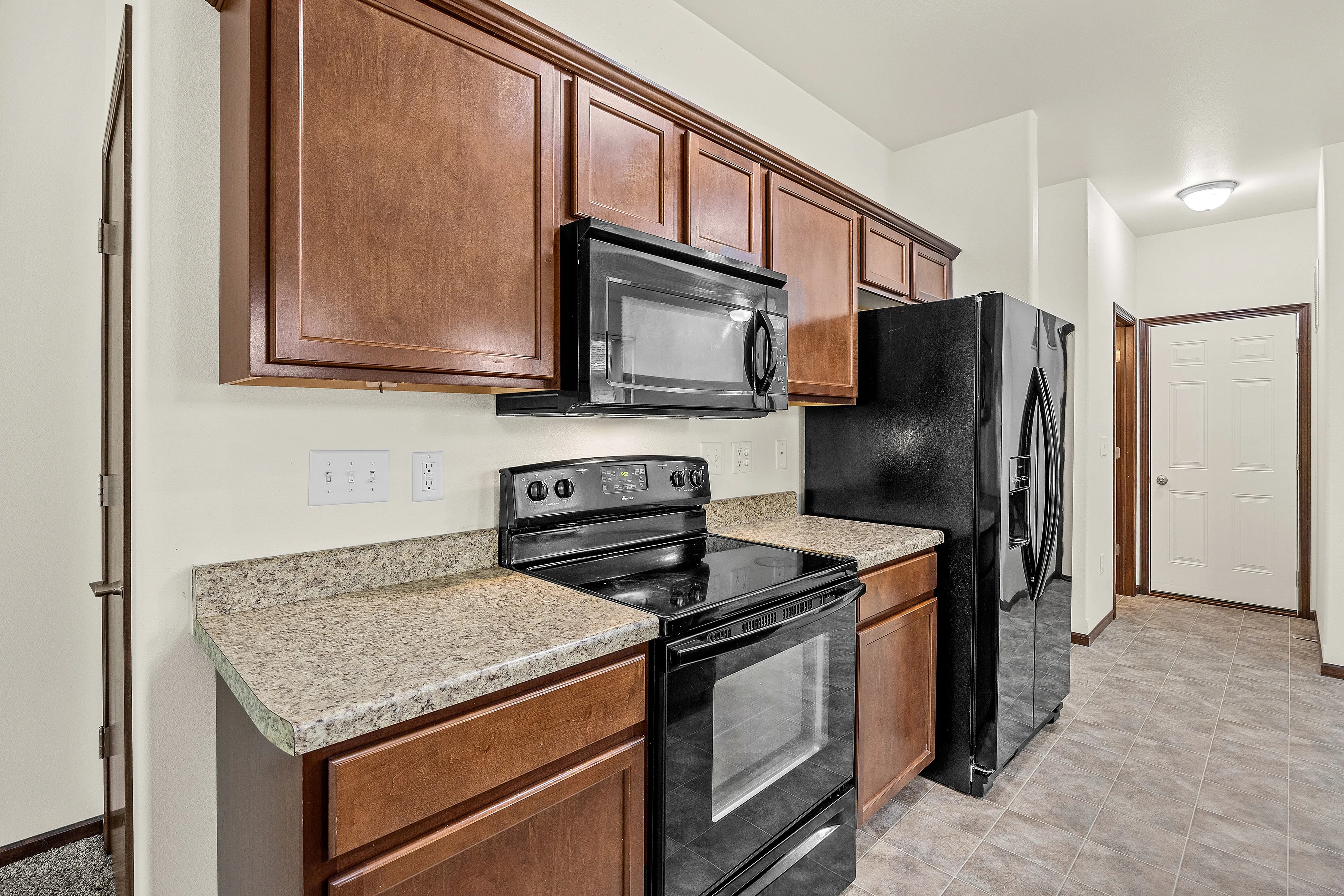 Modern kitchen with sleek black appliances, rich wood cabinetry, and elegant granite countertops.
