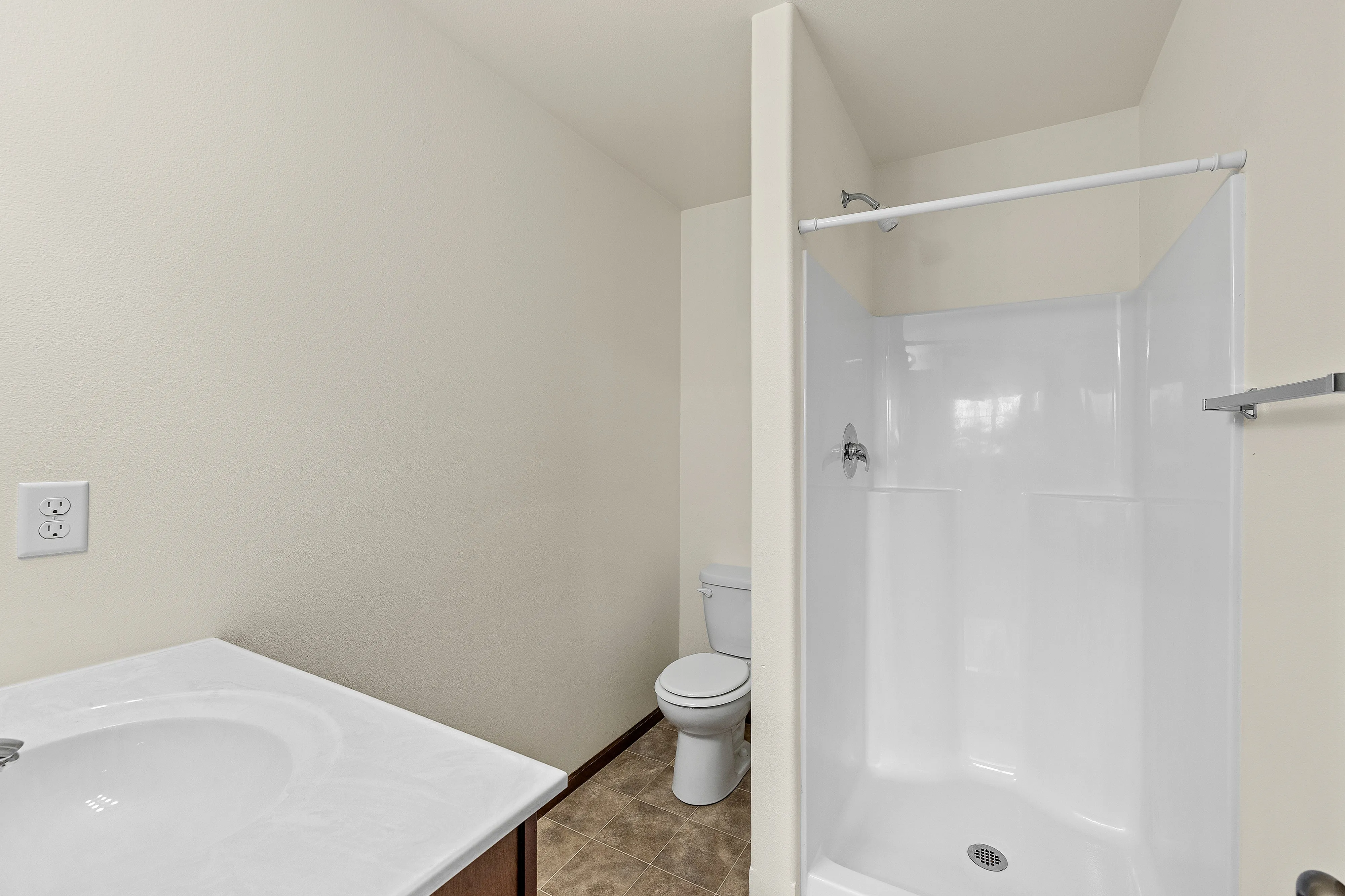 Bright and spacious bathroom featuring a modern shower, elegant sink vanity, and sleek tile flooring.
