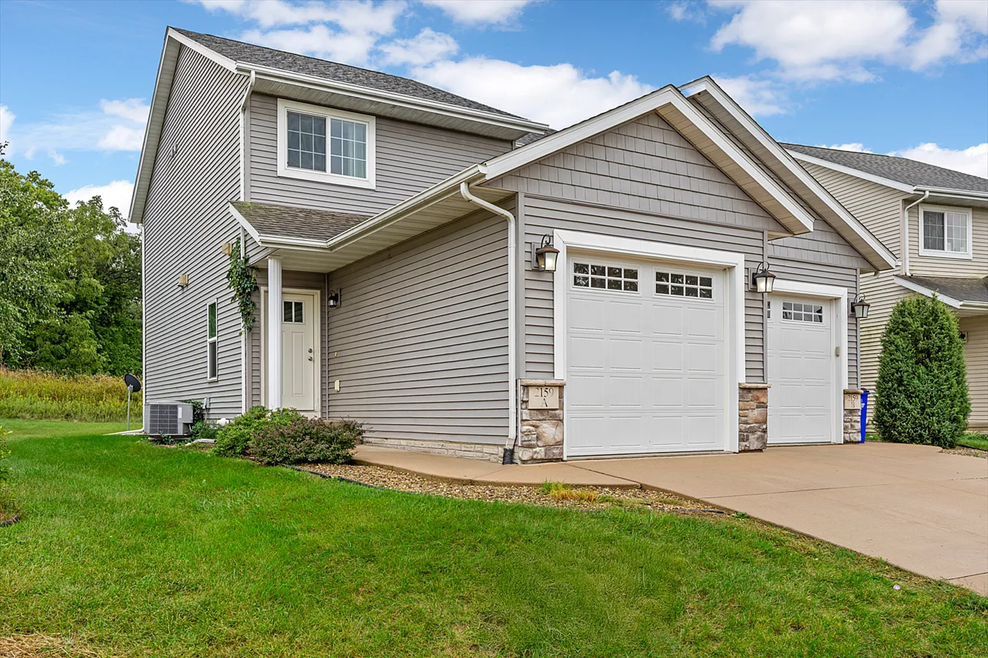 Charming two-story home with modern siding, lush green lawn, and attached garage, perfect for family living.