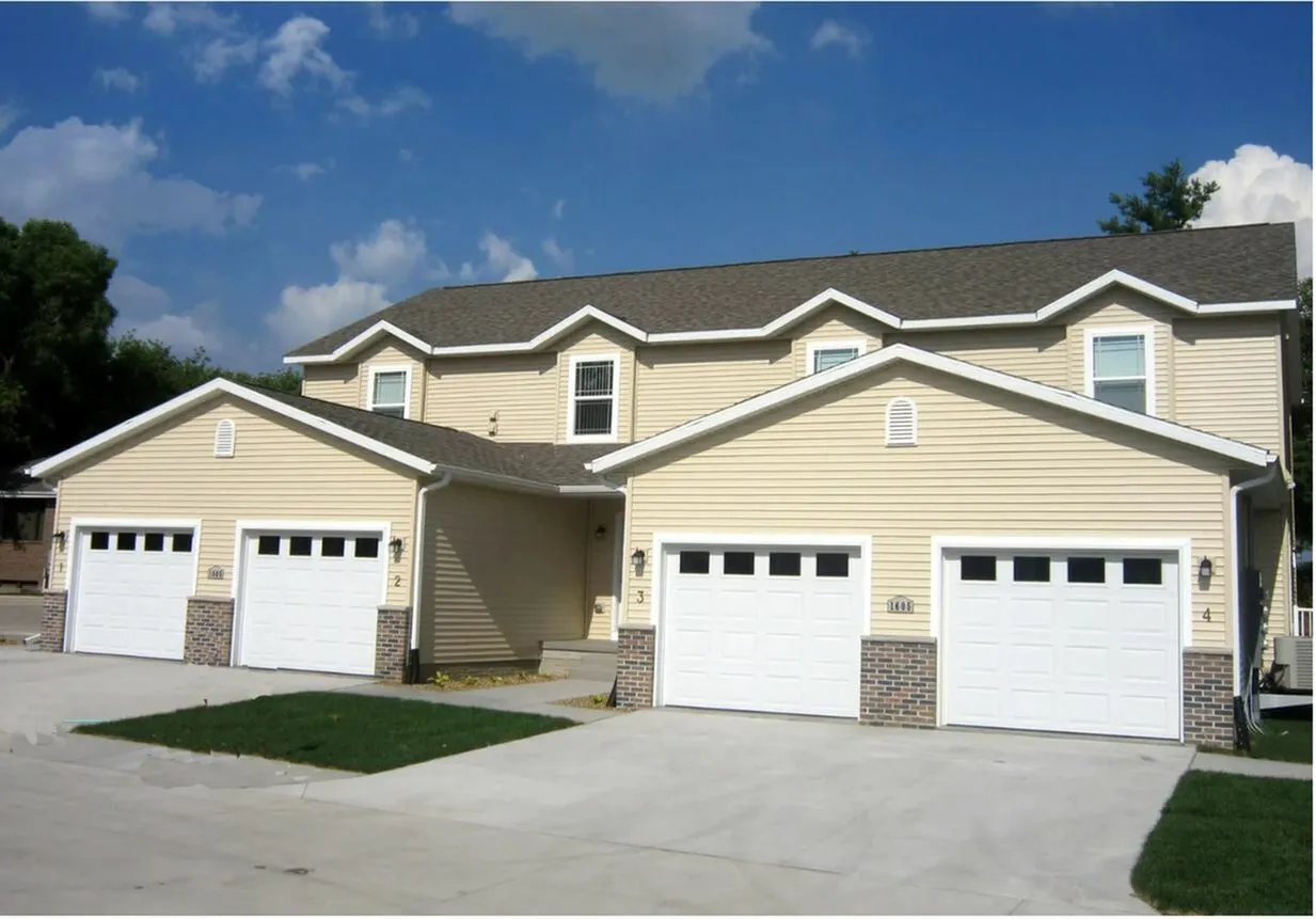Charming townhouse with multiple garages, featuring elegant architecture and a neatly maintained exterior under a clear blue sky.