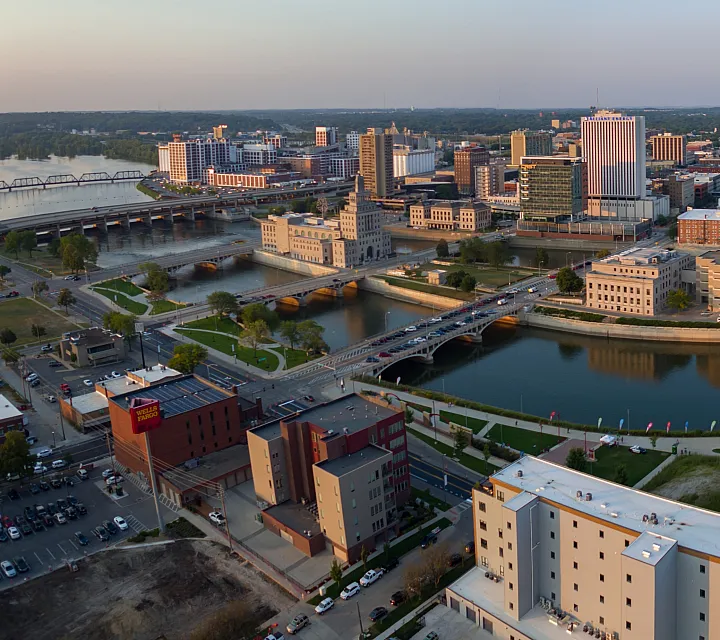 A stunning aerial view of a vibrant cityscape featuring a lively river, iconic bridges, and modern buildings under a clear sky.