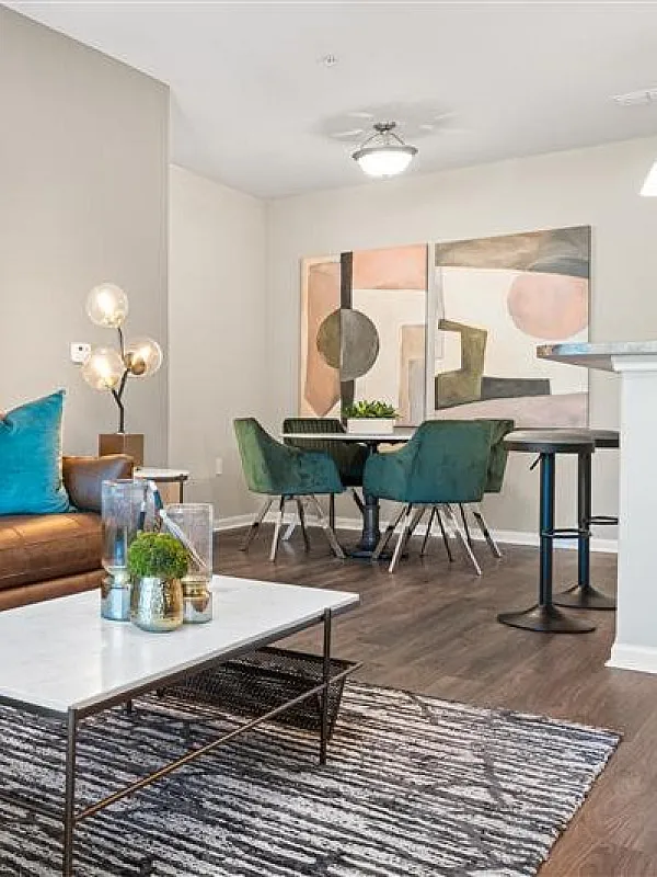 Chic living area with modern decor, featuring a comfortable brown leather sofa, stylish artwork, elegant dining space, and contemporary lighting.