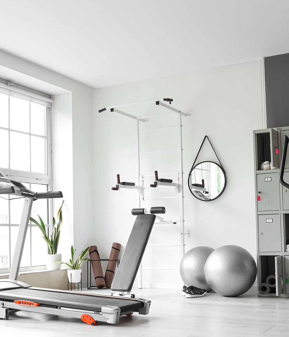 Bright and modern gym room with large windows, featuring treadmills, an exercise bike, and yoga mats for a refreshing workout experience.