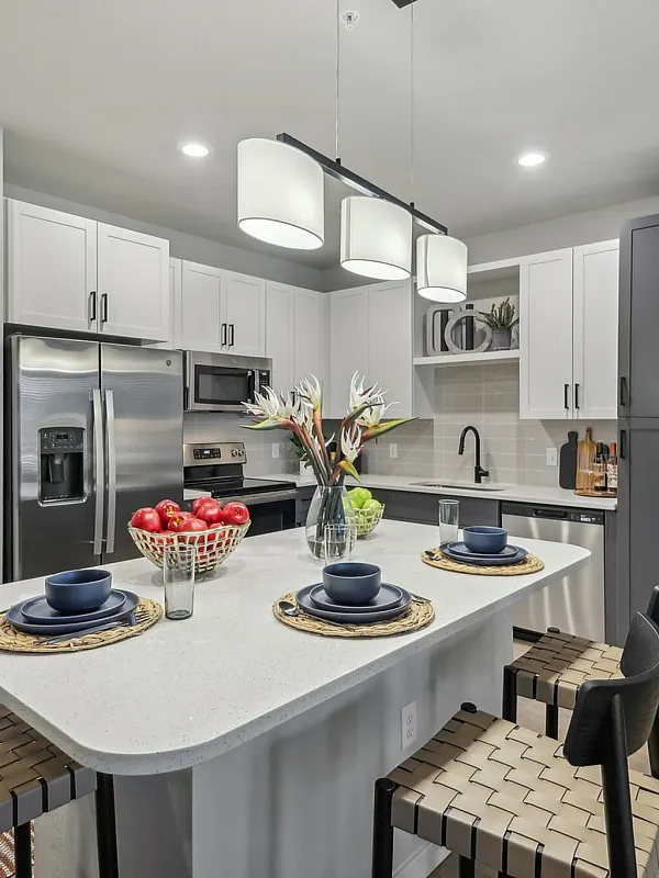 Modern kitchen with a sleek island, stylish stools, stainless steel appliances, and elegant lighting.
