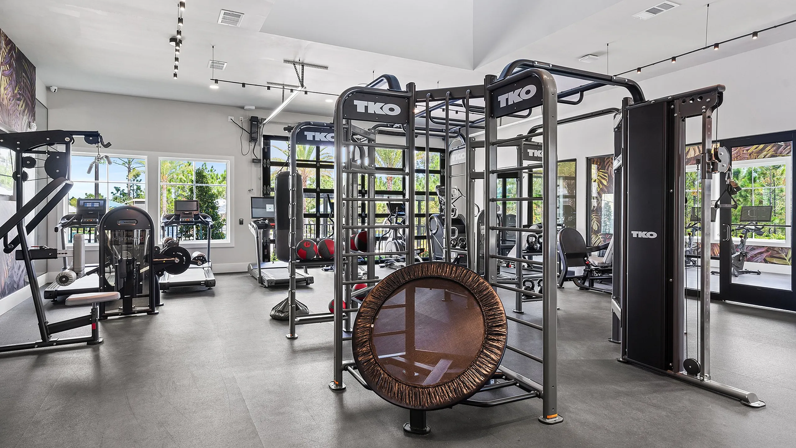 Bright and modern fitness center equipped with state-of-the-art exercise machines, sleek design, and large windows showcasing lush outdoor views.