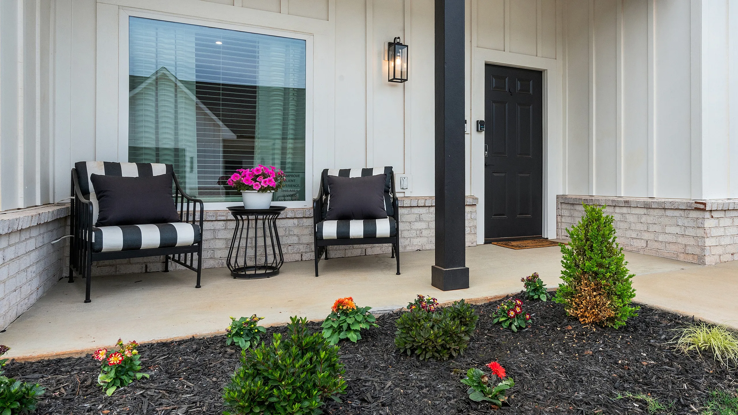 Charming front porch with elegant striped seating and vibrant flowers, creating a welcoming entrance.