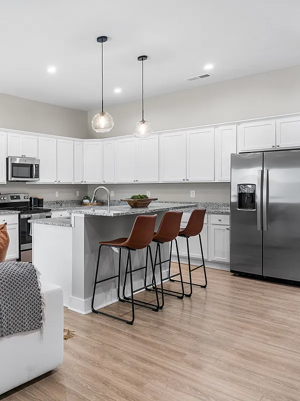 Contemporary open-plan living area with sleek kitchen, elegant white cabinetry, and cozy lounge featuring stylish decor and modern appliances.