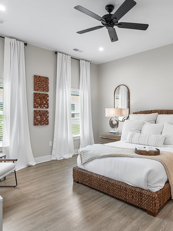 Elegant bedroom with wicker bed frame, modern decor, and warm natural lighting.