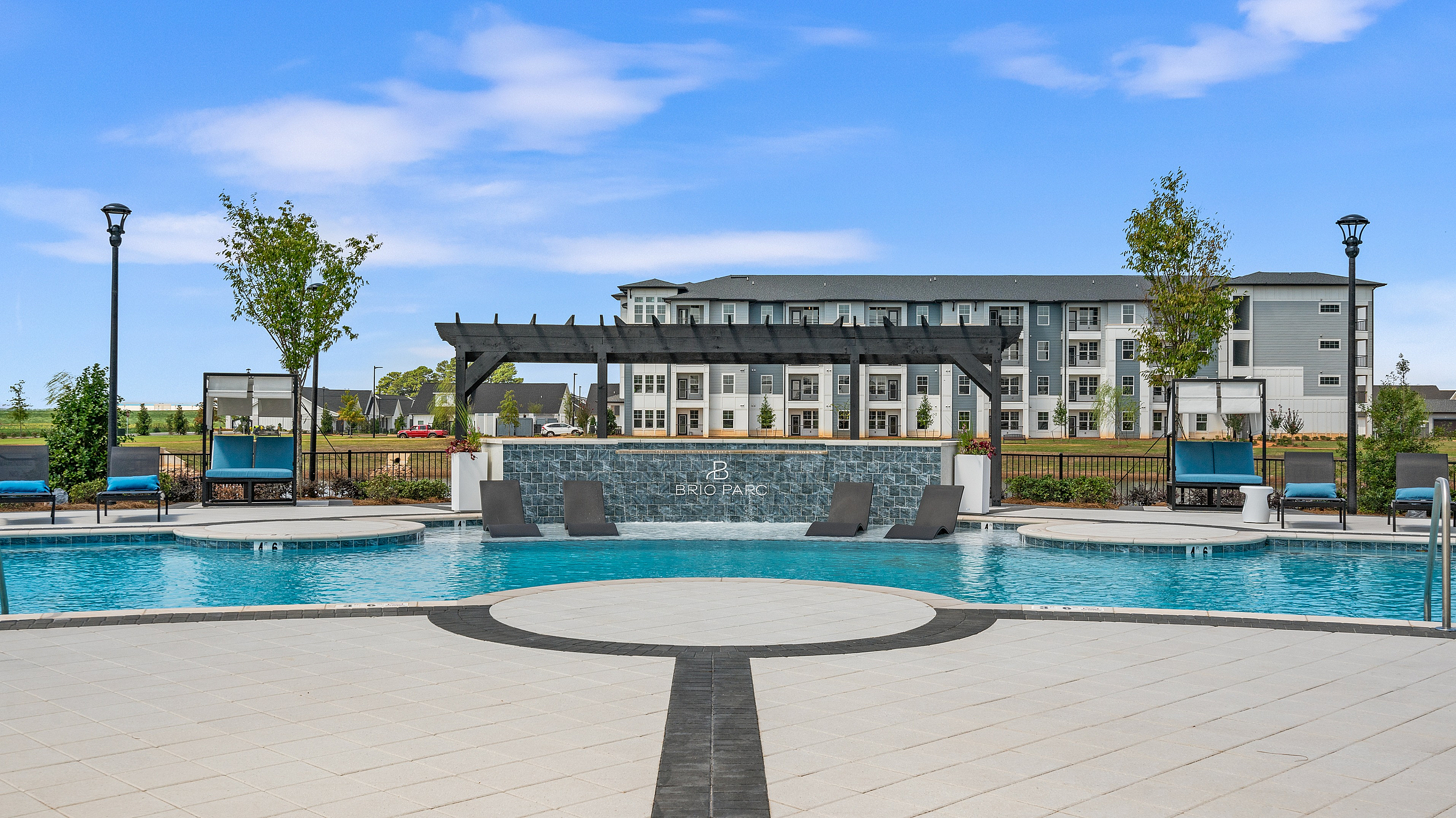 Luxurious apartment complex with stunning outdoor pool area, chic lounge seating, and elegant landscaping.