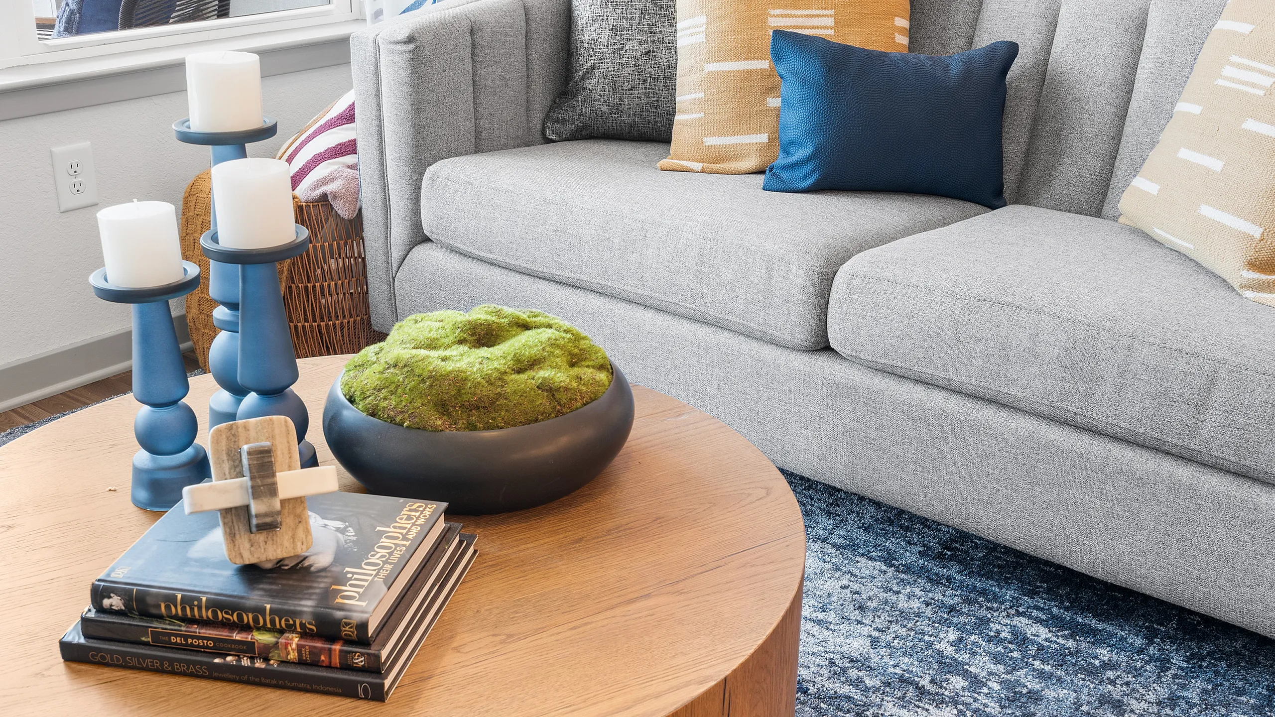 Chic living room with a stylish gray sofa, vibrant cushions, and a modern round coffee table adorned with elegant decor.