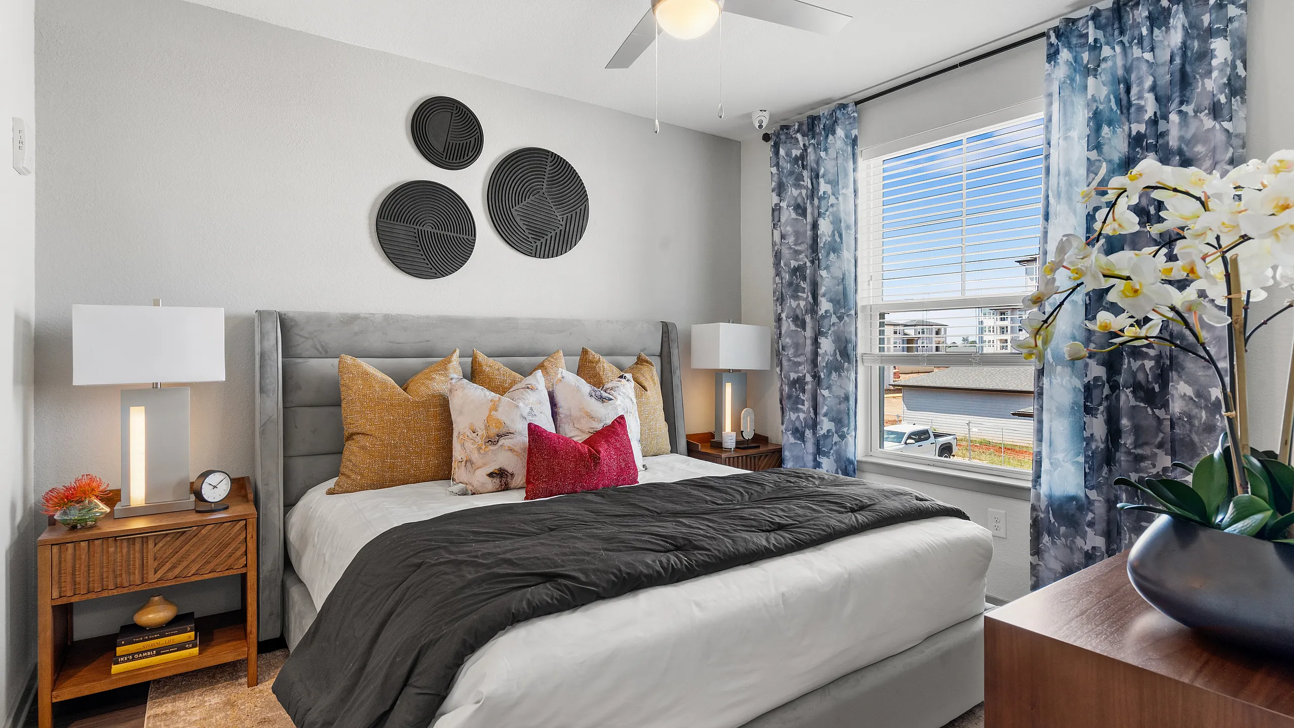 Chic bedroom with a stylish bed adorned with plush pillows, modern bedside lamps, and large window with elegant curtains, creating a serene and inviting atmosphere.