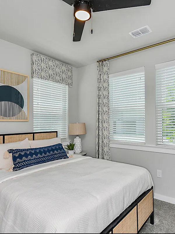 Inviting bedroom with elegant decor, featuring a plush bed, chic artwork, and ample natural light through stylish window treatments.