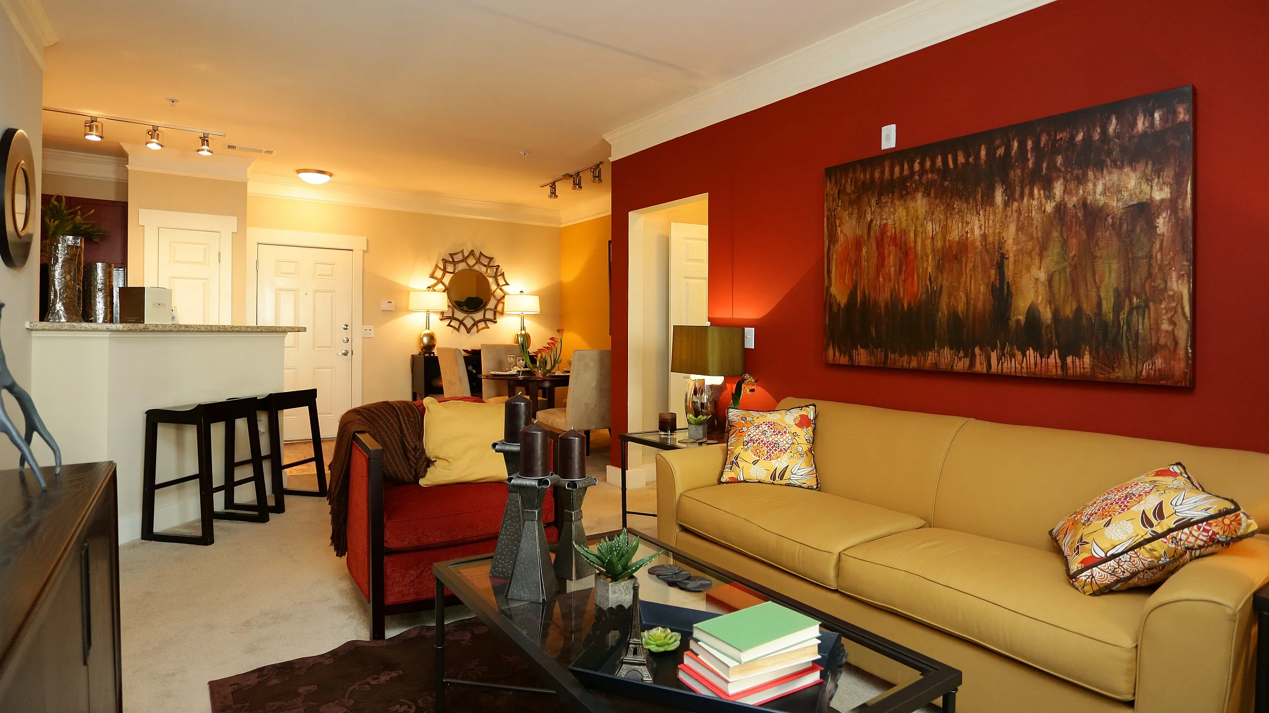 Inviting living room showcasing vibrant red and beige decor, modern art, and comfortable seating for a cozy atmosphere.