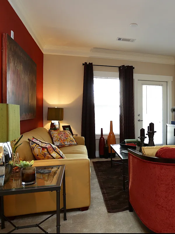 Chic apartment living room with colorful accents, featuring modern decor and a welcoming ambiance, leading into a cozy bedroom.