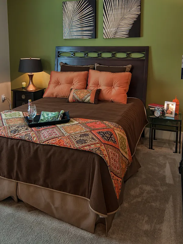 Cozy bedroom featuring an elegant dark wood bed frame, vibrant patterned bedspread, and warm lighting for a relaxing ambiance.