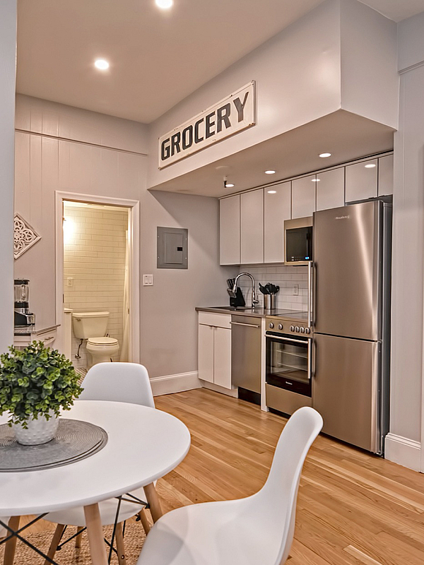 Chic apartment kitchen with modern stainless steel appliances, stylish dining area, and wooden flooring. Inviting decor with a cozy atmosphere.