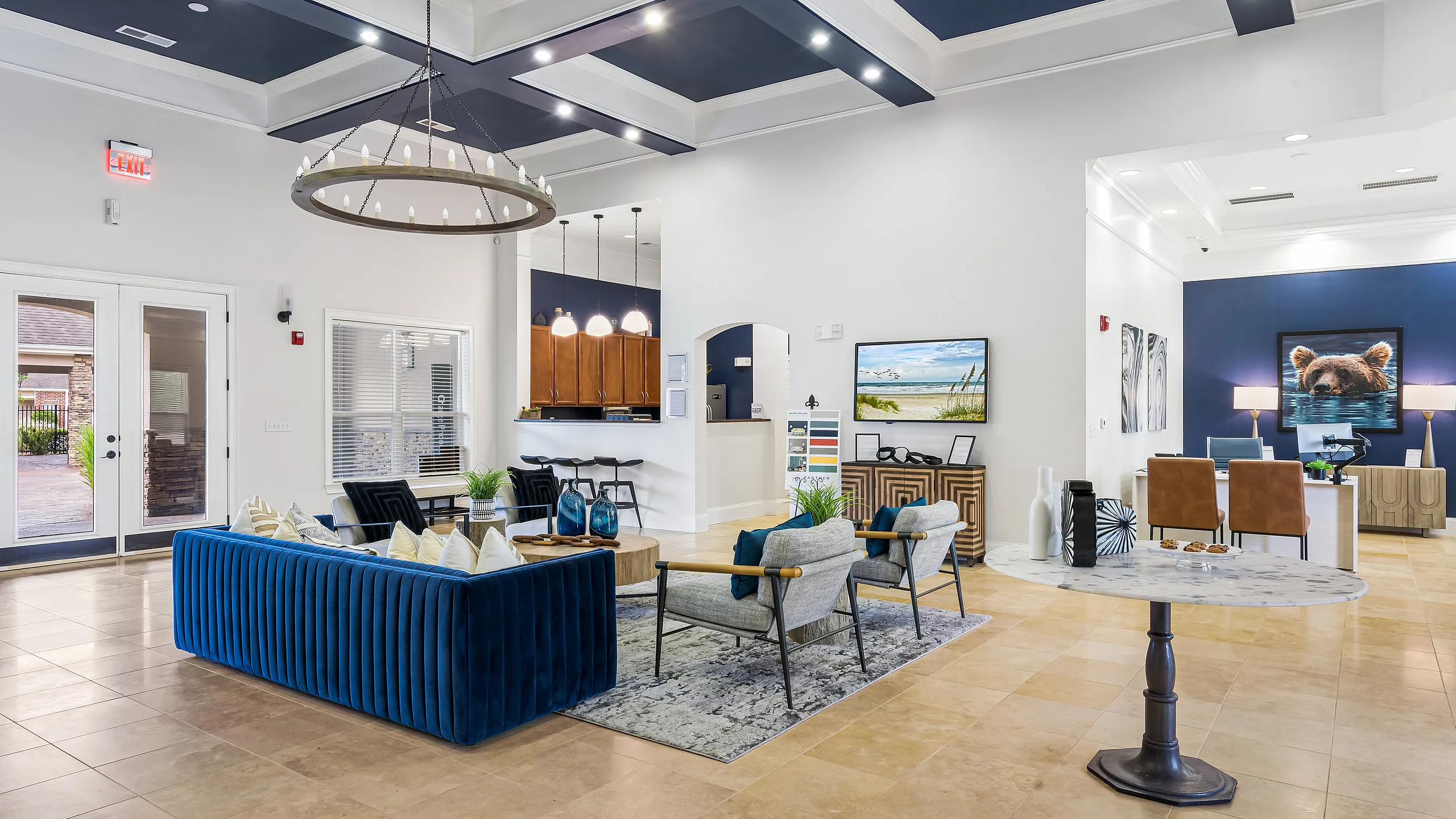 Bright and spacious living area with modern blue and gray seating, elegant lighting fixtures, and a sleek open-concept design.