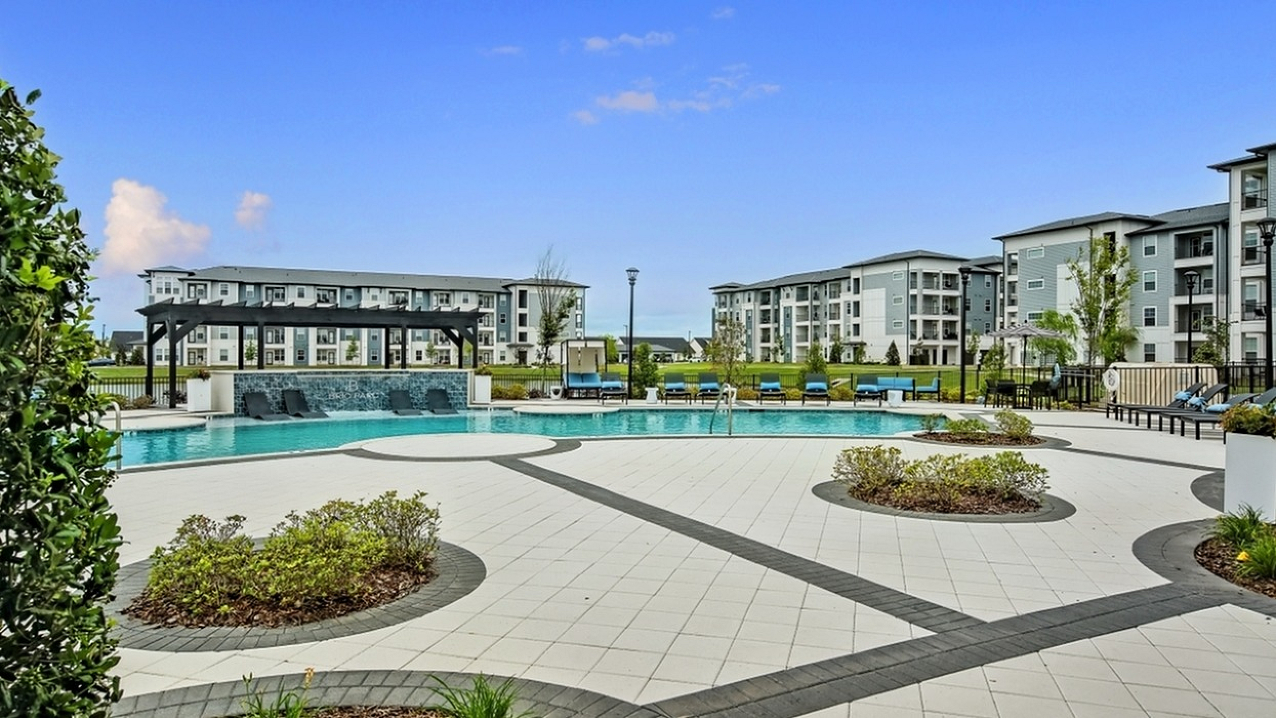 Luxurious apartment complex with a stunning outdoor pool area, surrounded by modern buildings and lush greenery for a serene living experience.