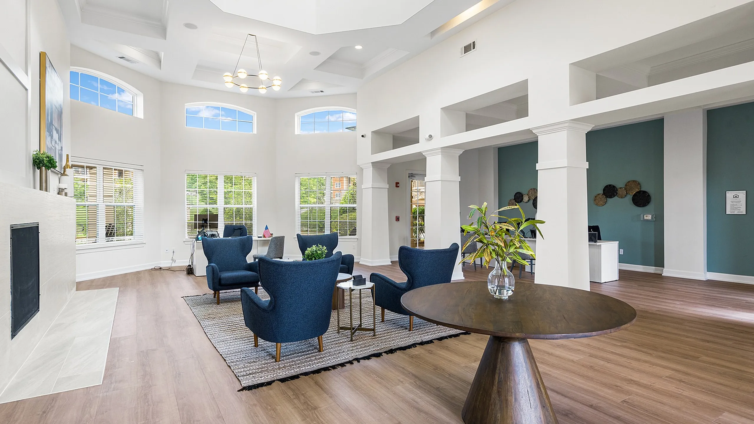 Elegant communal lounge featuring modern blue seating, high ceilings, and abundant natural light.